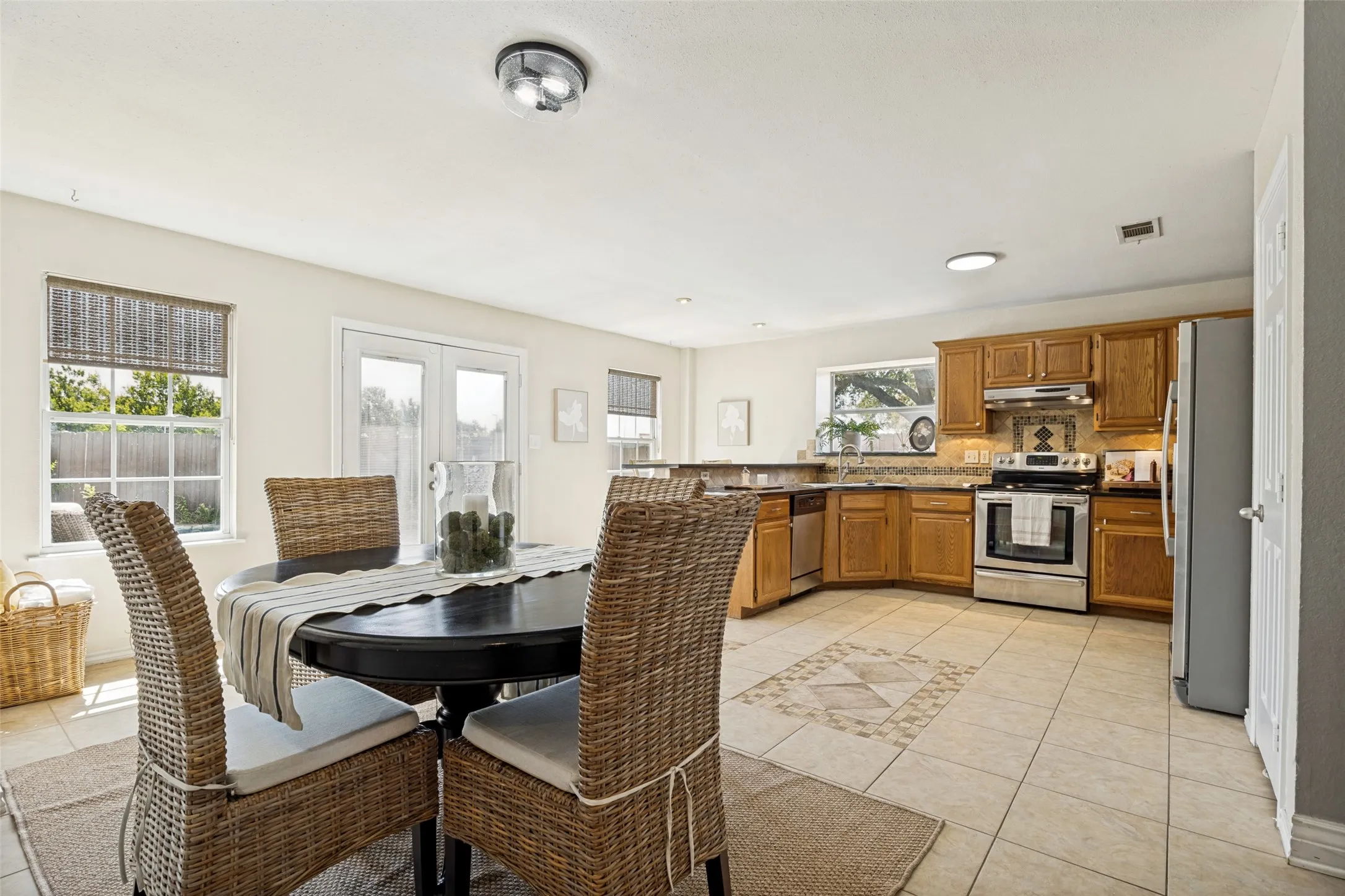 Open-concept kitchen featuring wood cabinetry, stainless steel appliances, and a tile backsplash