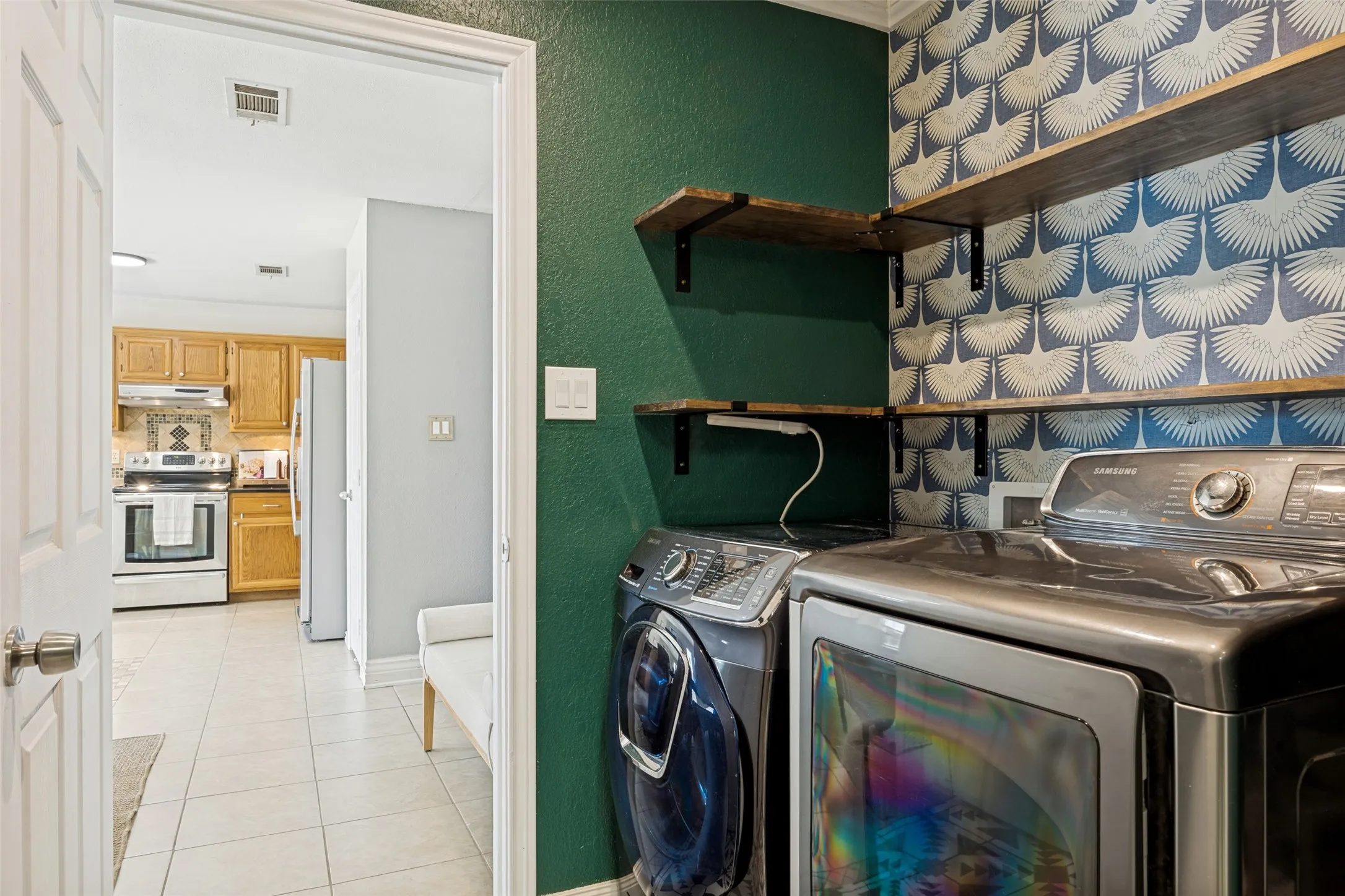 Built-in wood shelving with black metal brackets, patterned wallpaper, and a dark green accent wall