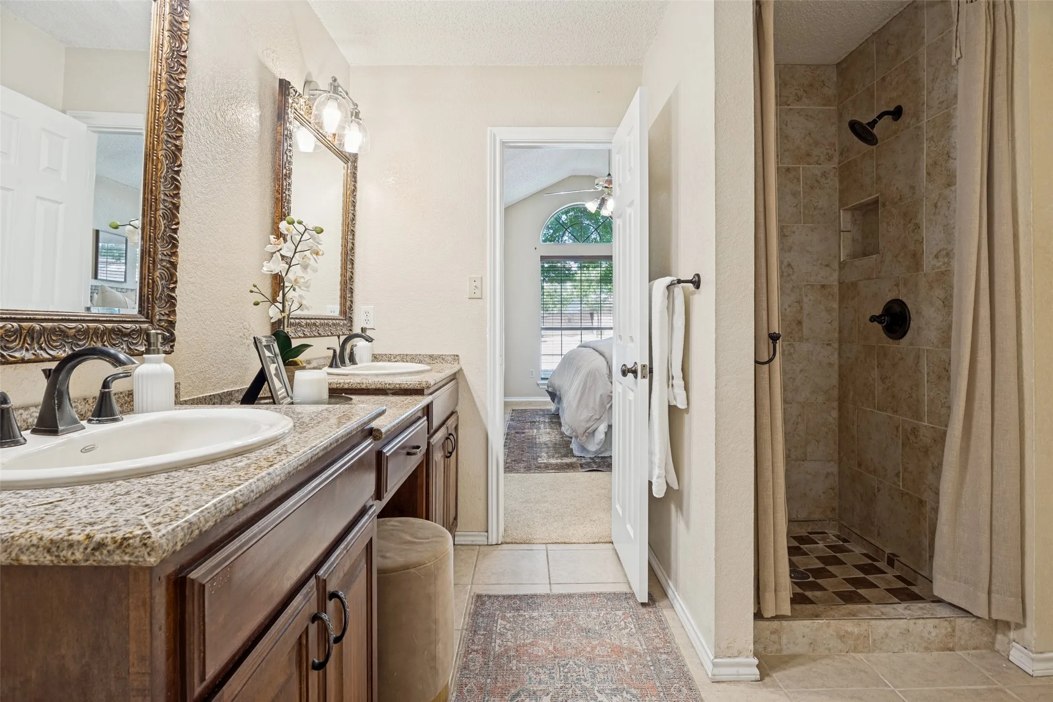 Double vanity with granite-style countertops, dark wood-finish cabinetry, and oil-rubbed bronze fixtures