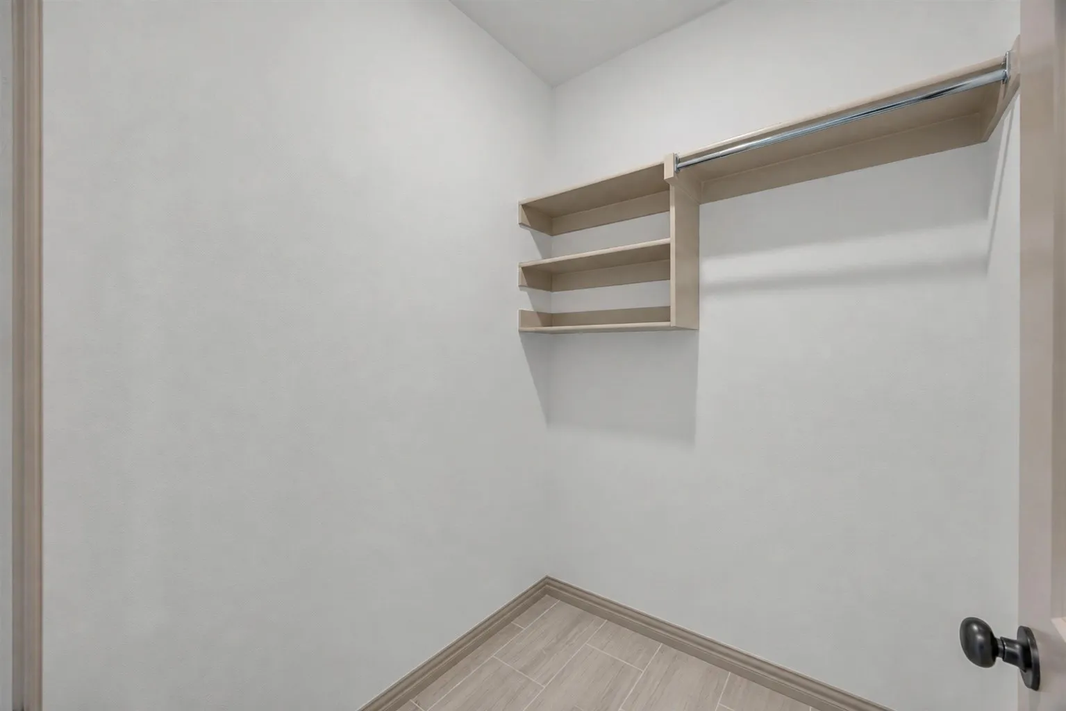 Built-in shelving with hanging rod, tile flooring, and neutral wall tones