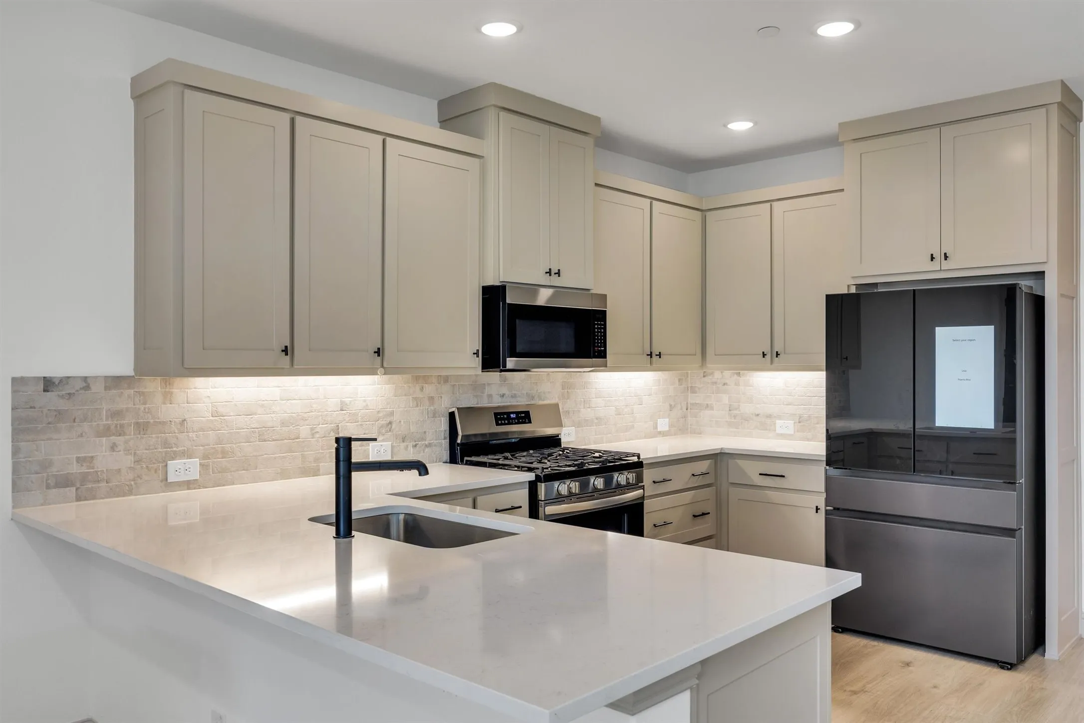 Modern kitchen featuring light-toned cabinetry, a subway tile backsplash, and recessed lighting