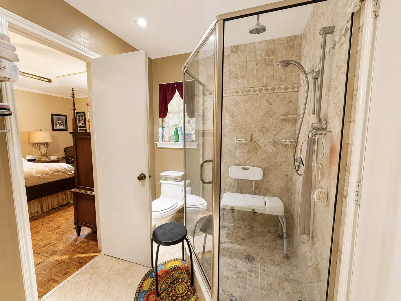 Glass-enclosed shower with a rainfall showerhead, handheld shower fixture, and tiled walls