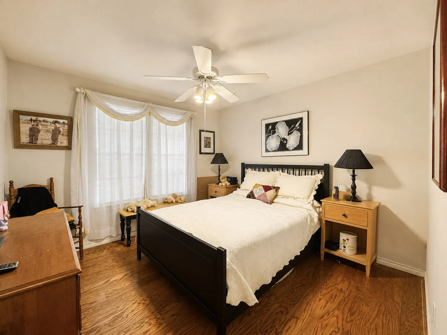 Wood-finish flooring, ceiling fan with integrated lighting, and multiple windows providing natural illumination