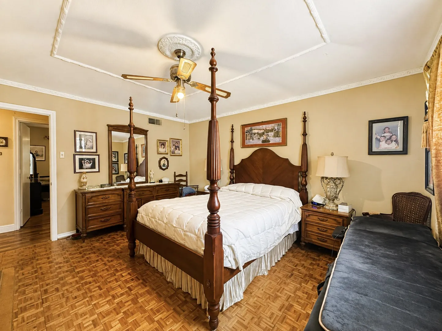 Parquet wood-finish flooring, tray ceiling with decorative molding, ceiling fan, and crown molding