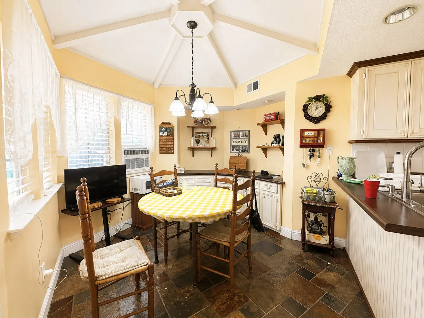 Octagonal vaulted ceiling with a central chandelier, tiled flooring, built-in cabinetry, and integrated sink