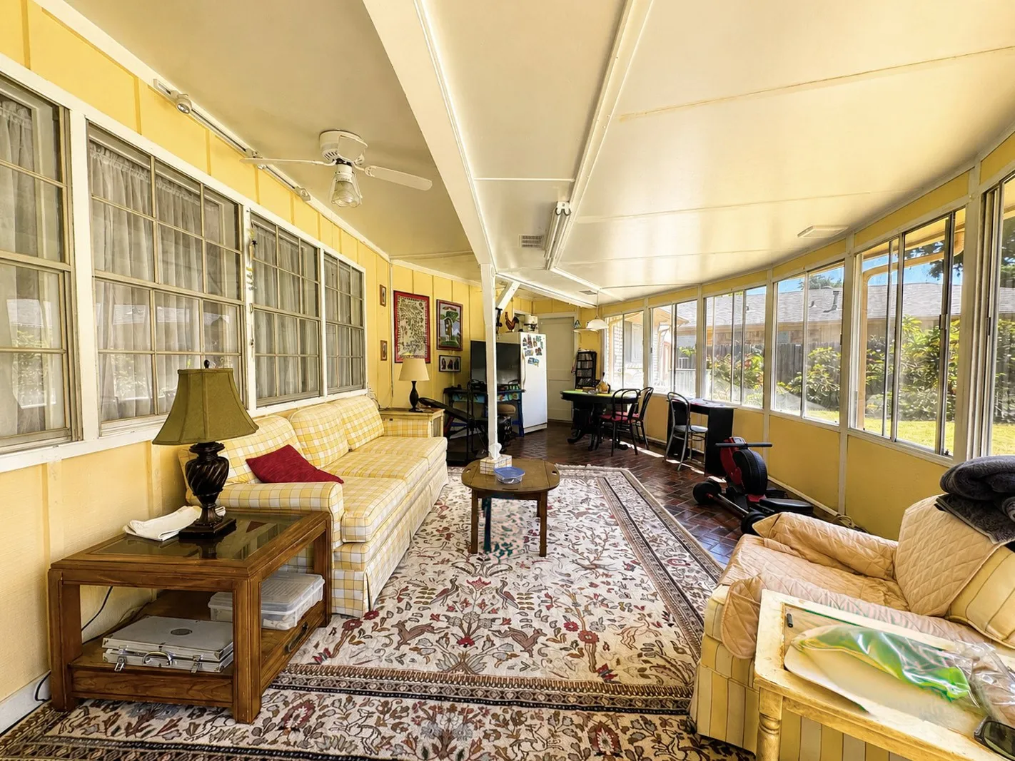 Enclosed sunroom with extensive window walls, a ceiling fan, and tile flooring