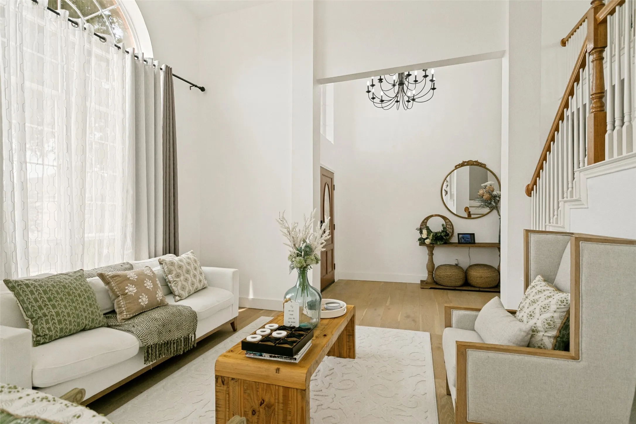 Bright, open living area featuring hardwood flooring, a wood-finish coffee table, and large windows with natural light