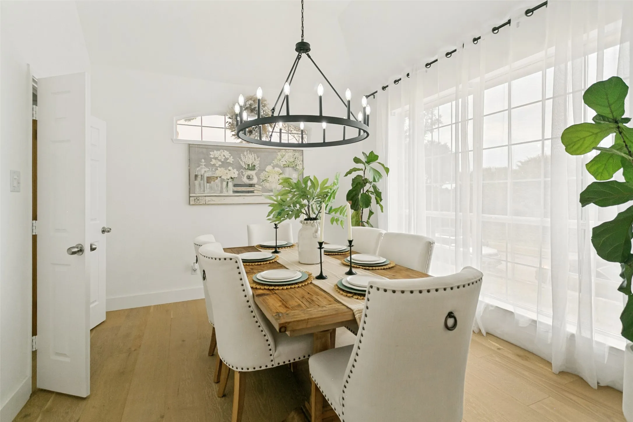 Vaulted ceiling with an iron chandelier, wood-finish flooring, and large windows with transom detail