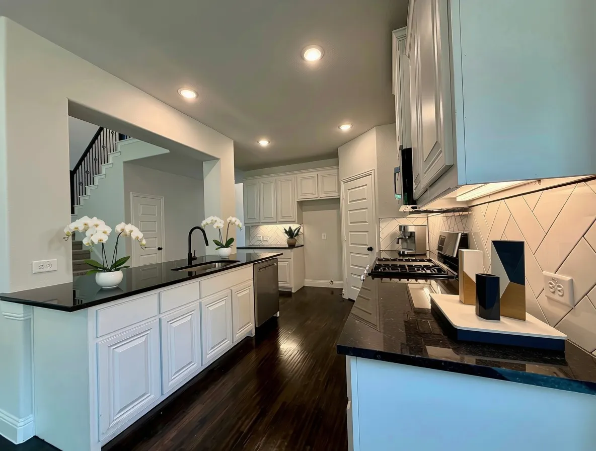 Clean modern kitchen white raised panel abinets and black granite counters
