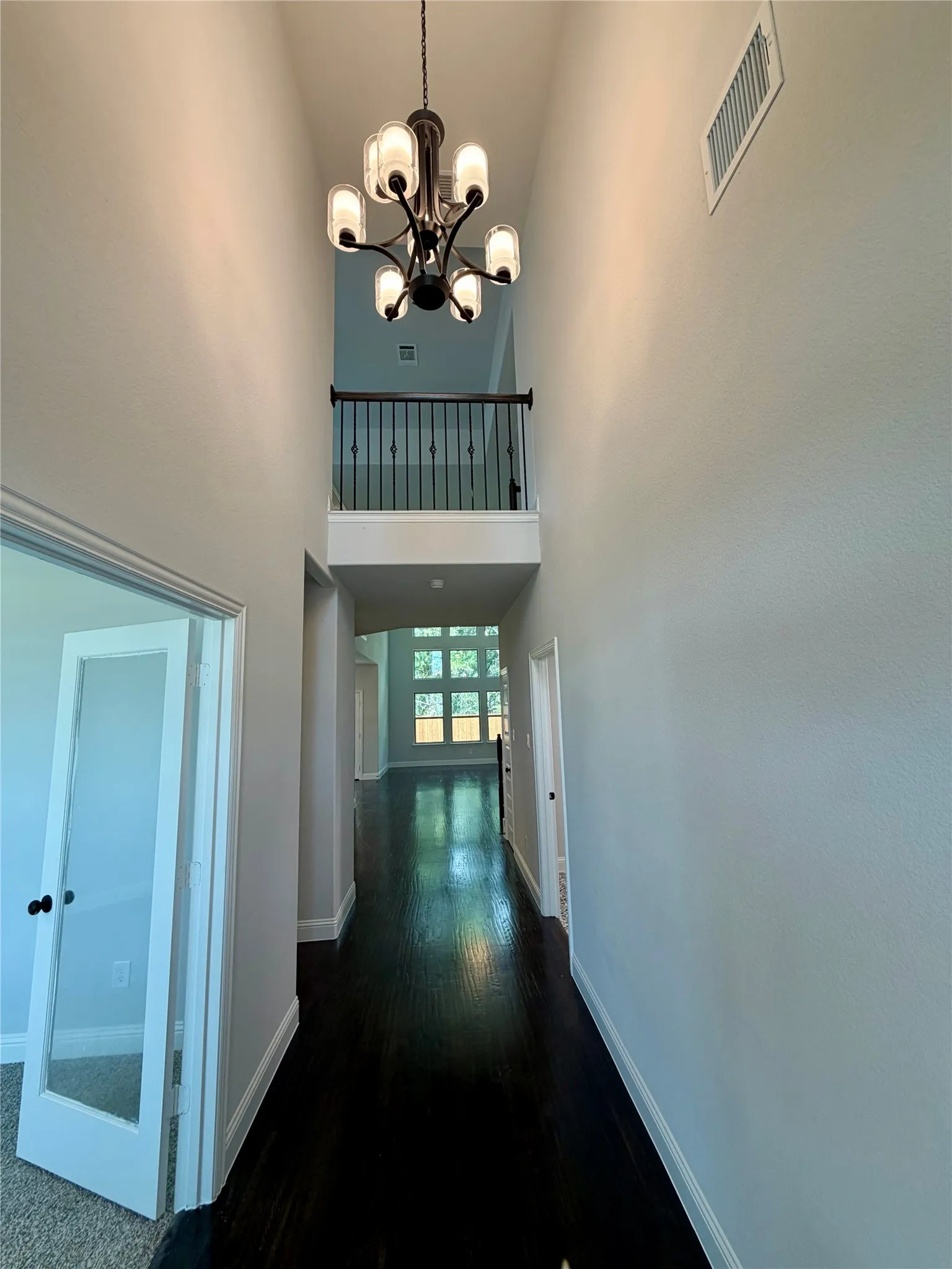 Cathedral entry with ebony hardwoods and matte black chandelier