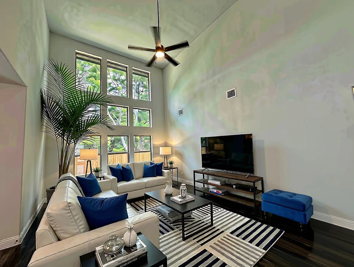 Huge wall of windows looking at trees in Family room with cathedral ceilings, hardwoods, and ceiling fan
