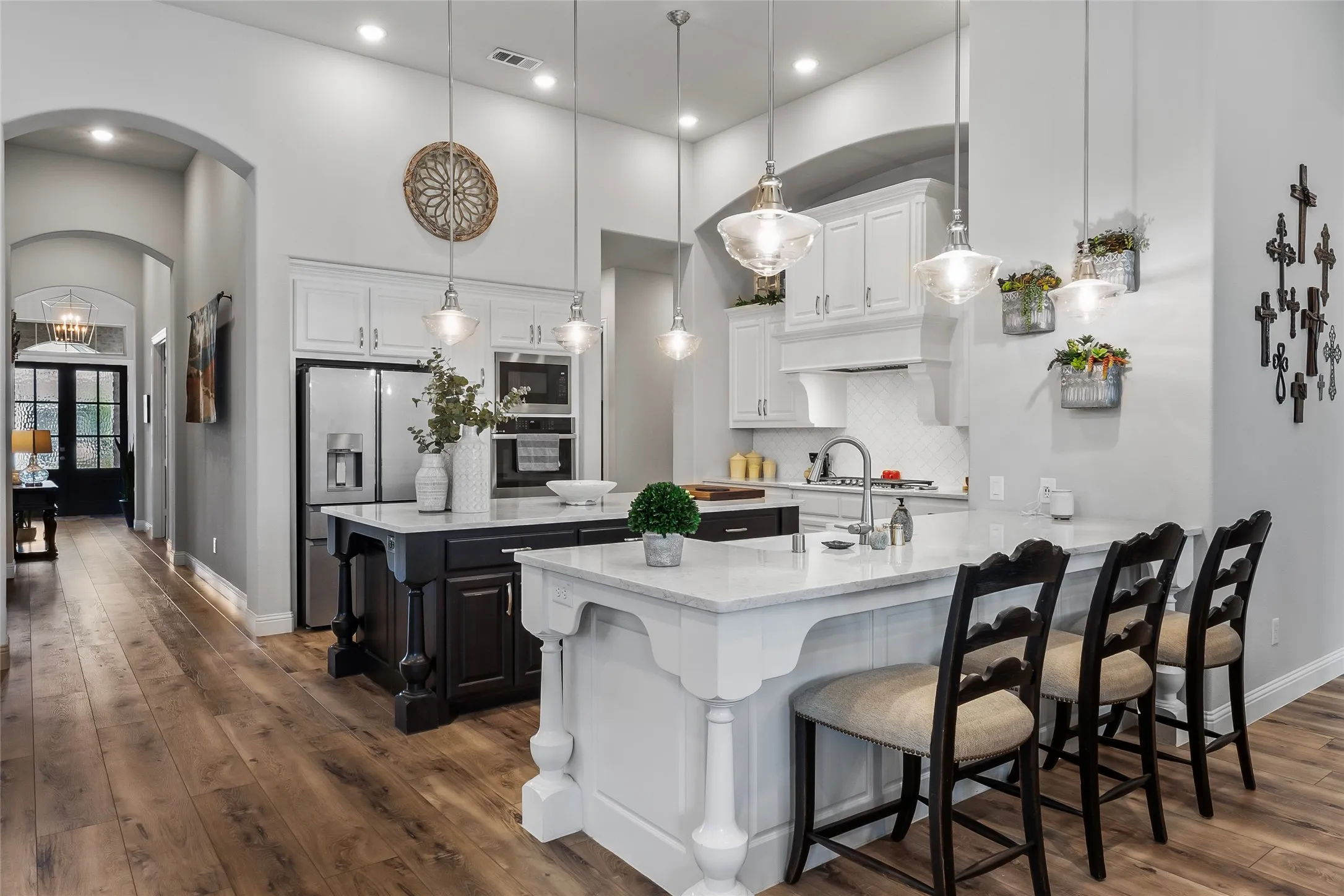 Kitchen with dark hardwood / wood-style flooring, a breakfast bar, stainless steel appliances, white cabinetry, and hanging light fixtures