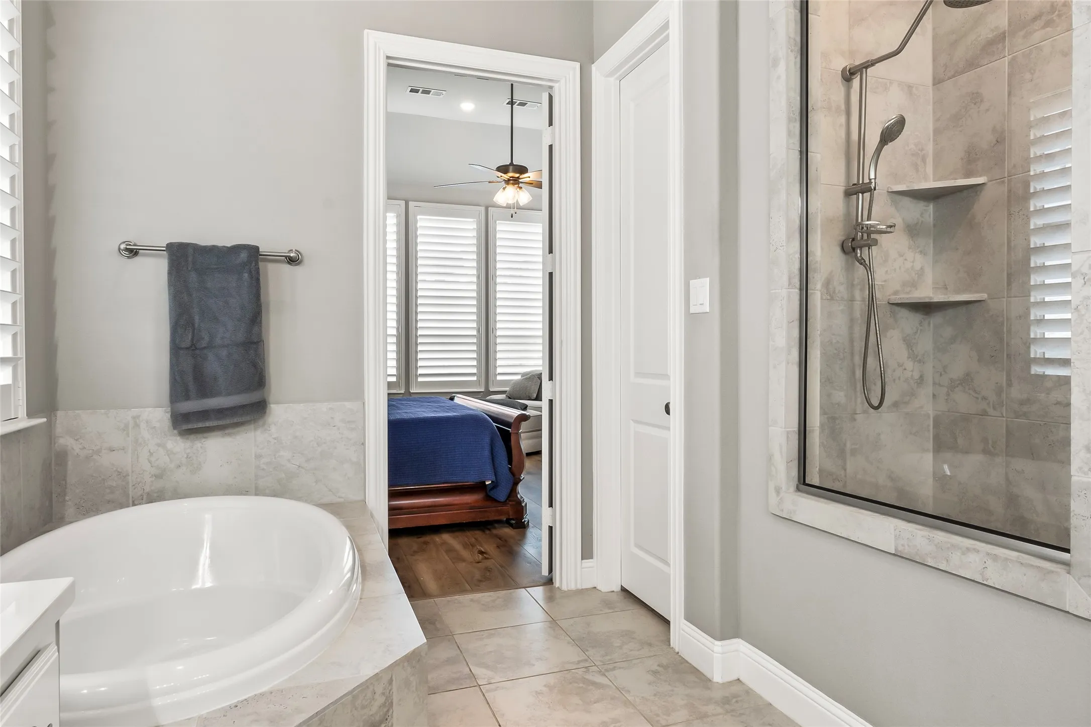 Bathroom with tile patterned flooring, vanity, ceiling fan, and plus walk in shower