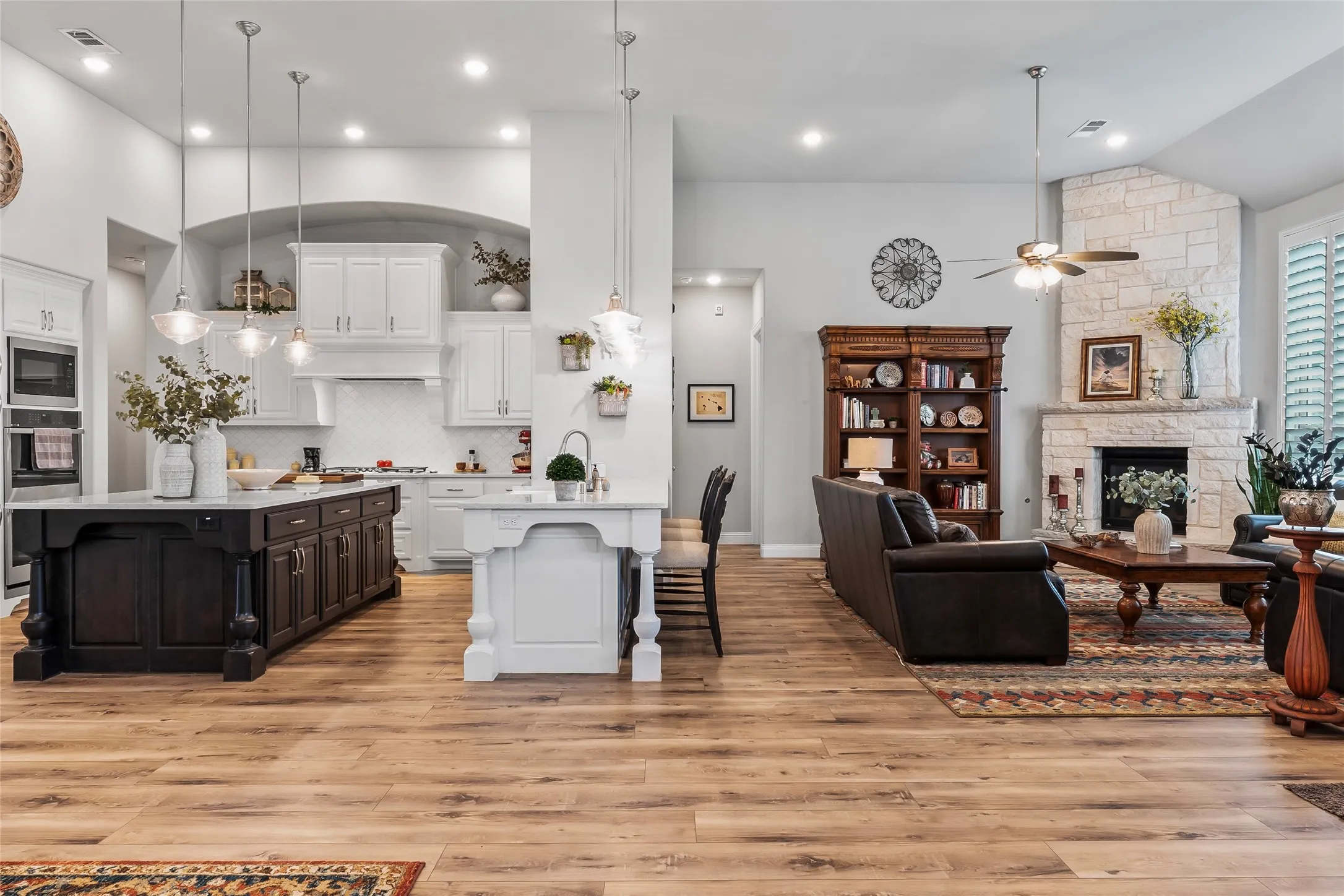Kitchen with white cabinetry, stainless steel microwave, a kitchen breakfast bar, light hardwood / wood-style flooring, and decorative light fixtures