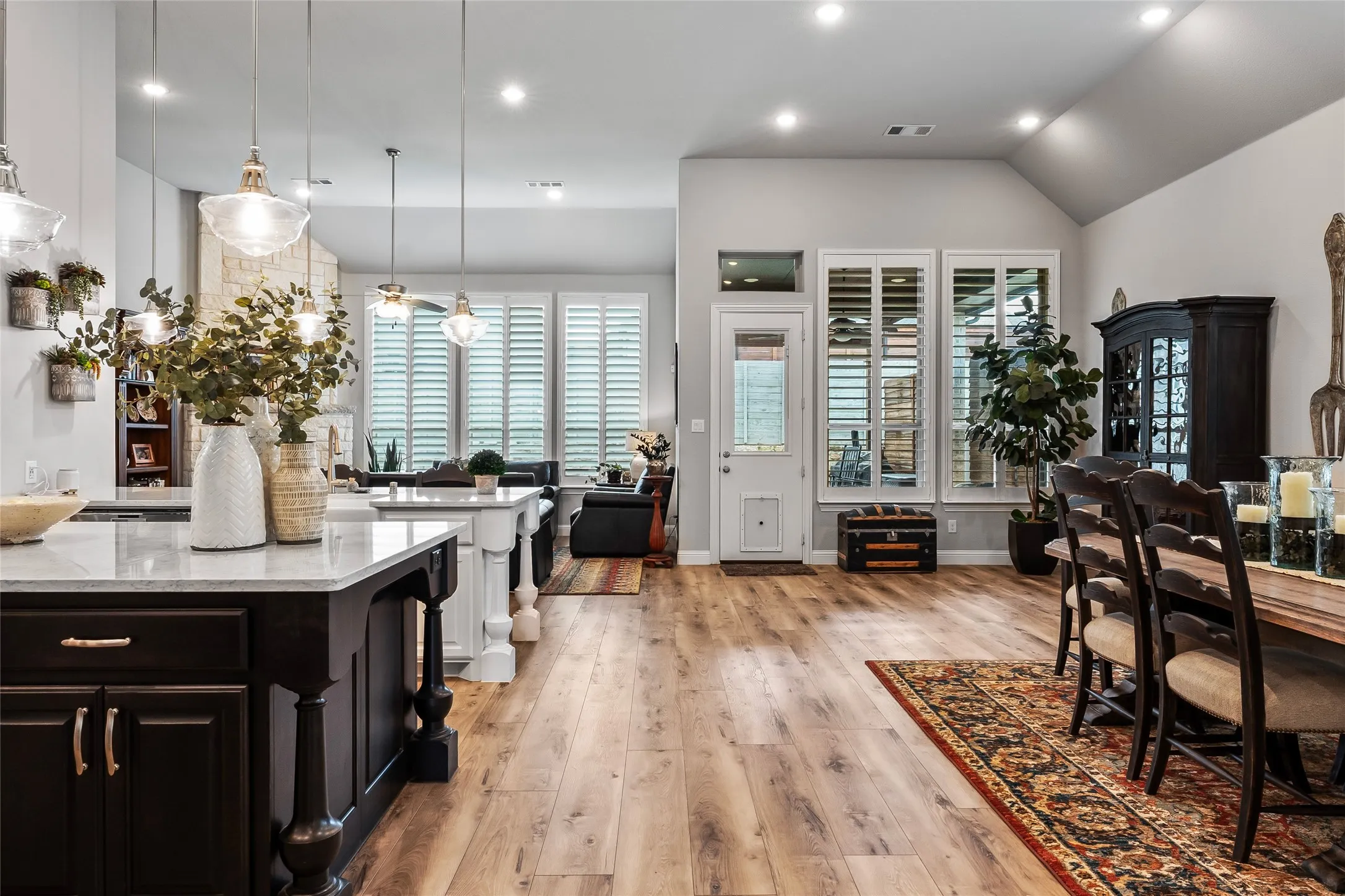 Kitchen featuring hanging light fixtures, light stone counters, light hardwood / wood-style flooring, lofted ceiling, and a breakfast bar