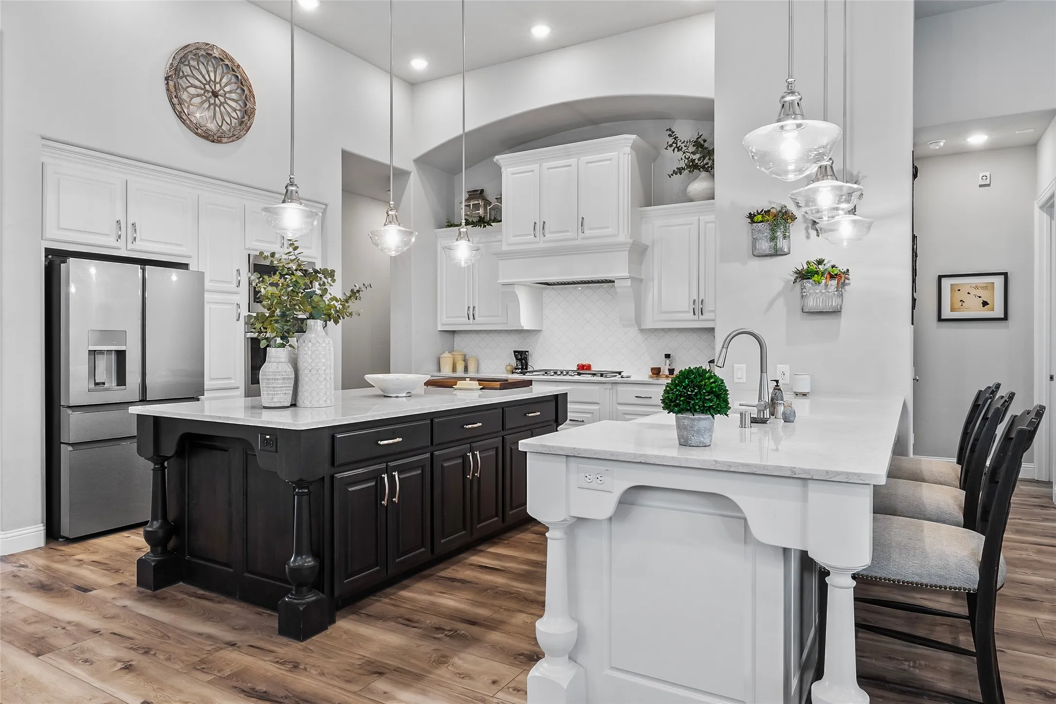 Kitchen featuring appliances with stainless steel finishes, a kitchen island with sink, pendant lighting, hardwood / wood-style flooring, and white cabinets