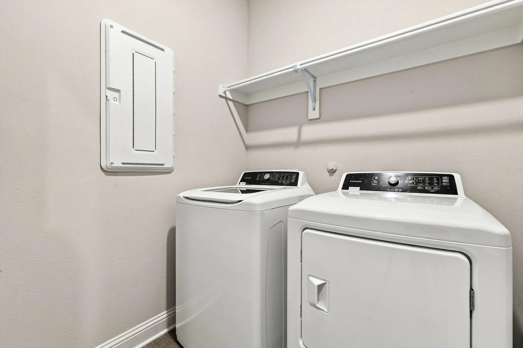 Laundry area featuring a top-load washing machine and front-load dryer with a white wall-mounted shelf