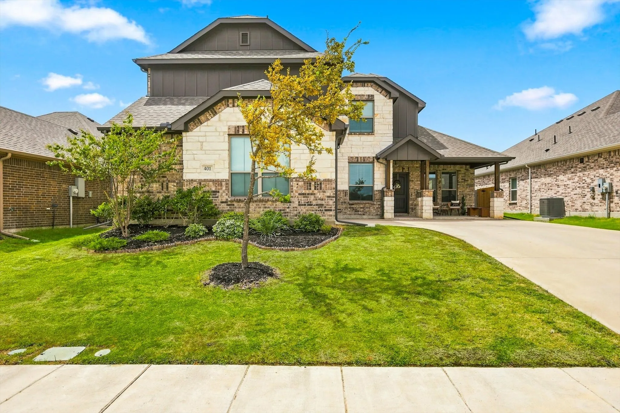 Two-story exterior with brick and stone accents, covered front porch, and an attached two-car garage