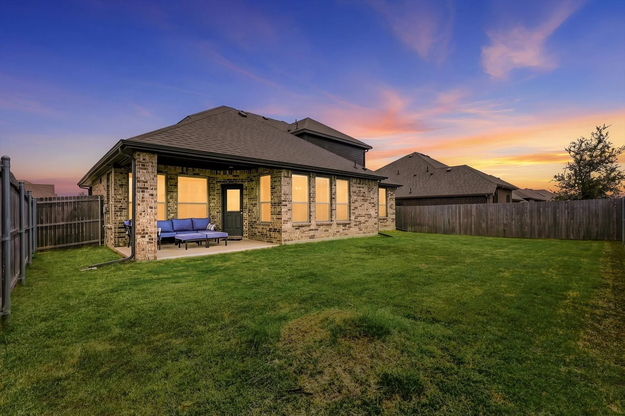 Expansive backyard with a manicured lawn, full privacy fencing, and a concrete patio