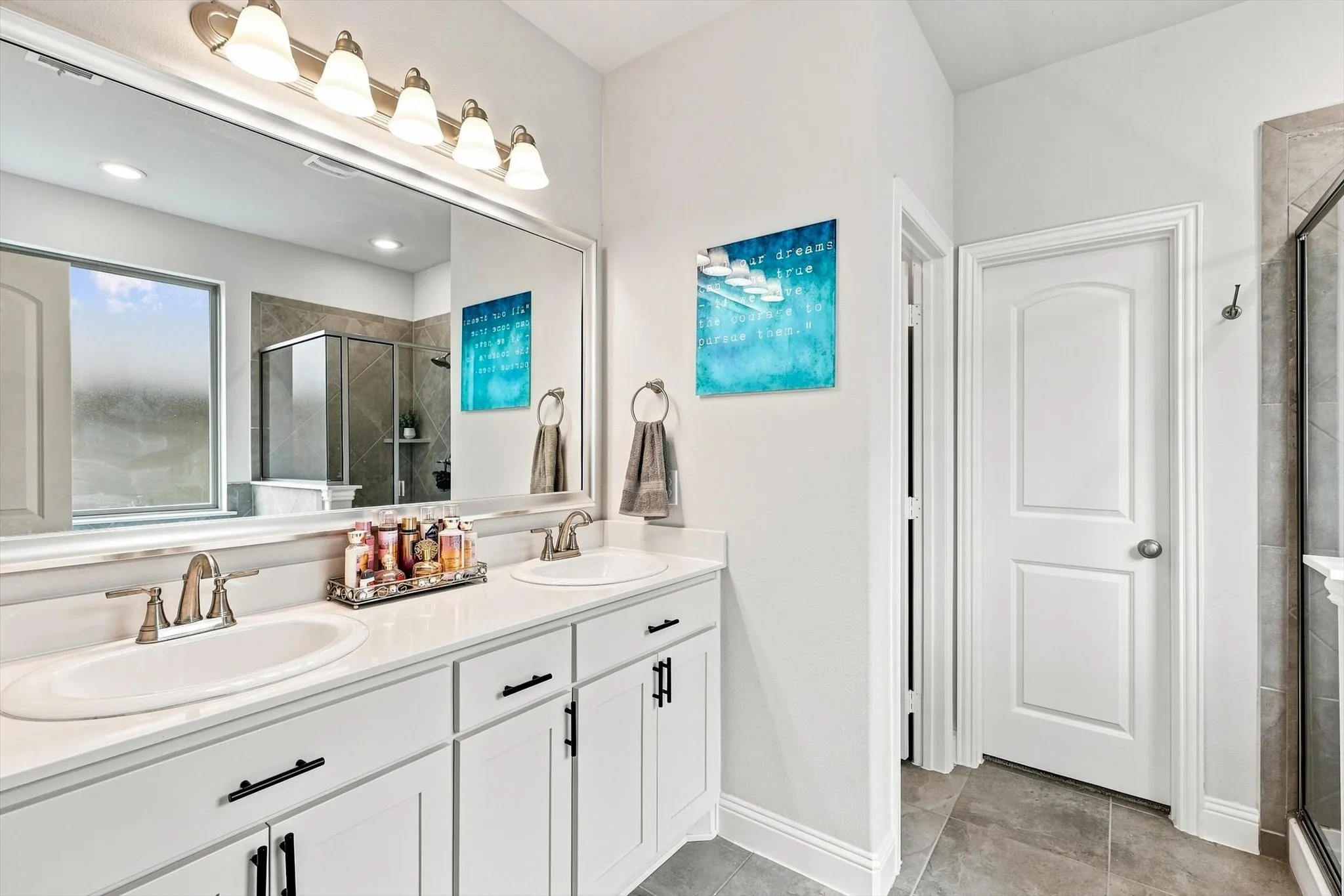 Dual vanity with white cabinetry, polished chrome fixtures, and a large mirror