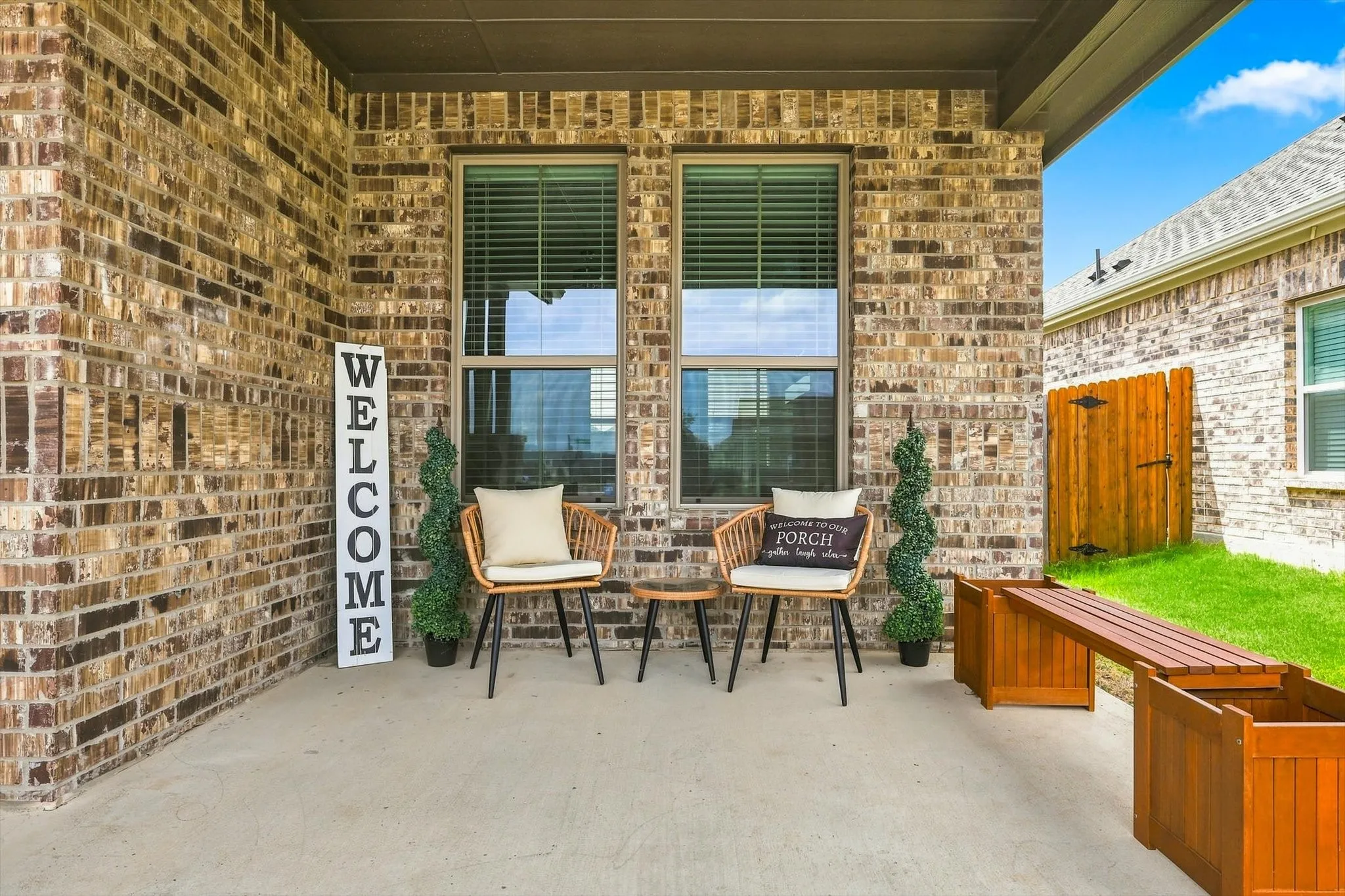 Covered concrete patio featuring brick exterior, dual pane windows, and a wooden privacy fence