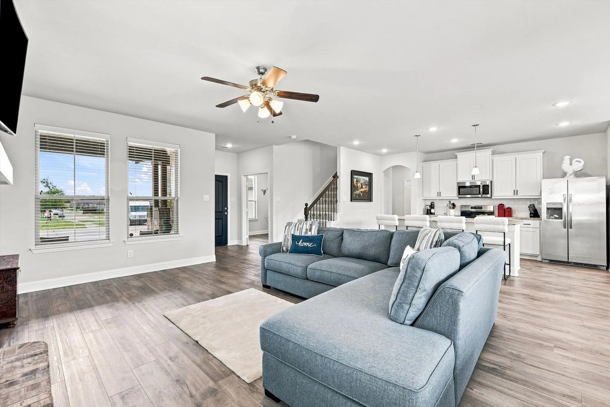 Open-concept living area with wood-finish flooring, recessed lighting, and a ceiling fan