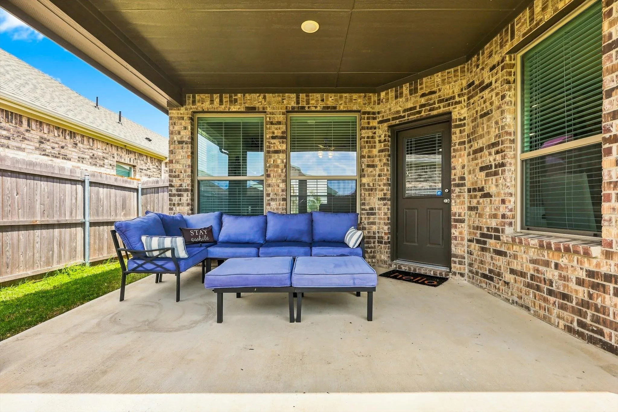 Covered back patio concrete featuring a brick exterior and wood privacy fencing