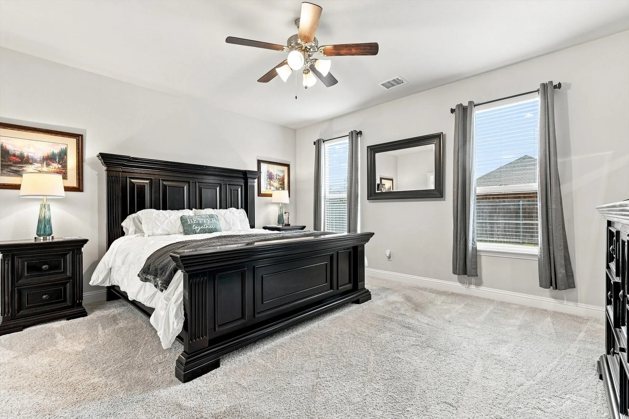 Spacious room with a ceiling fan, light-toned carpeting, and multiple windows with blinds