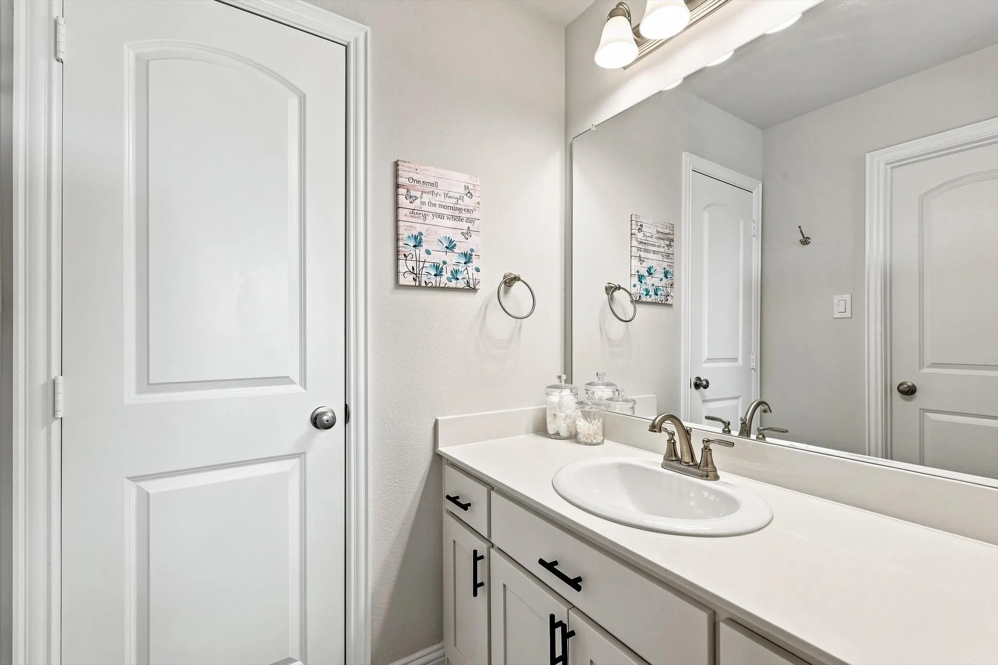Vanity with a white countertop and integrated sink, brushed nickel faucet, and a large wall-mounted mirror