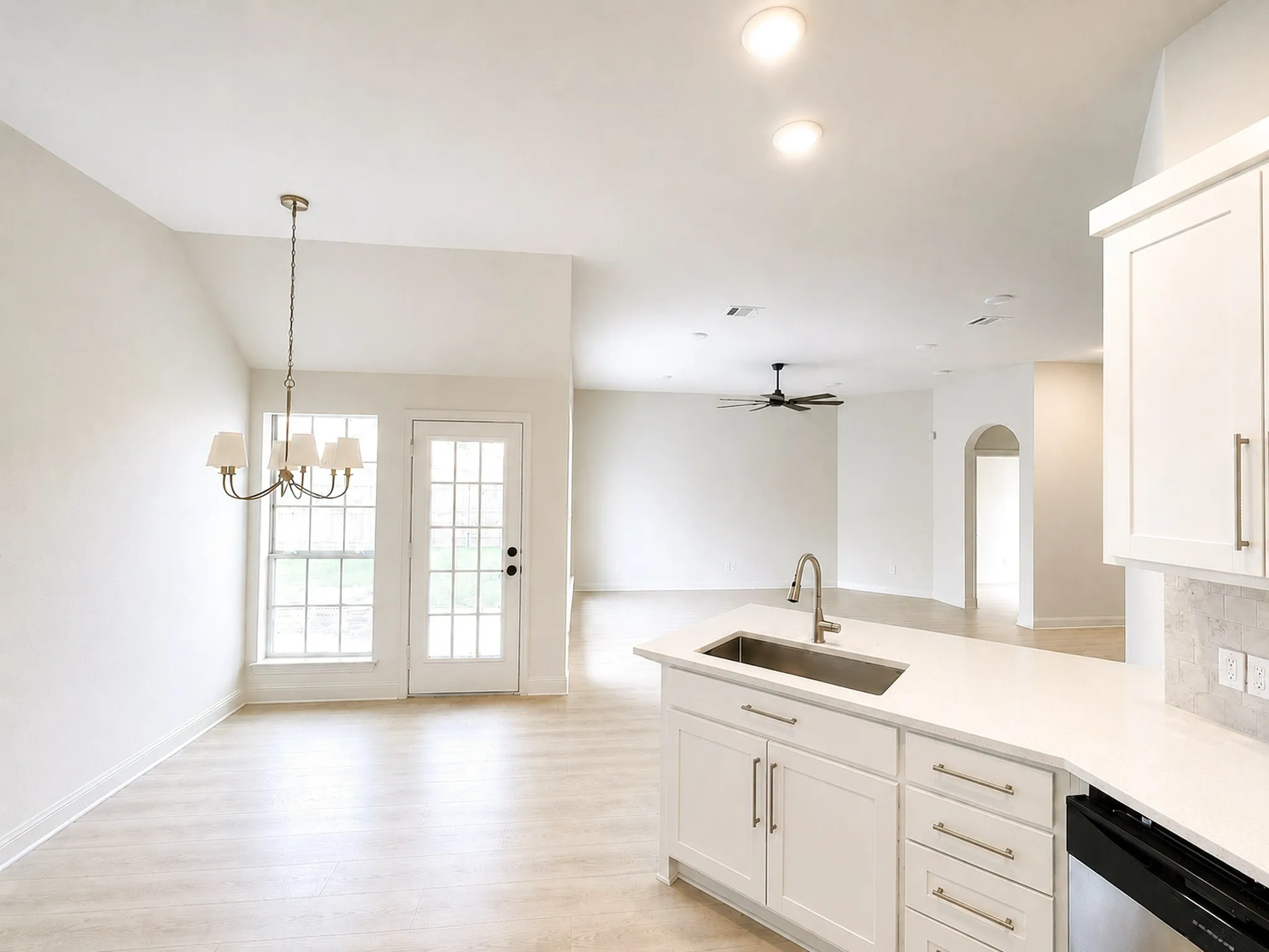 Bright, open-concept kitchen and living area with a large island, quartz countertops, stainless steel sink, custom cabinetry, and seamless flow for everyday living and entertaining.