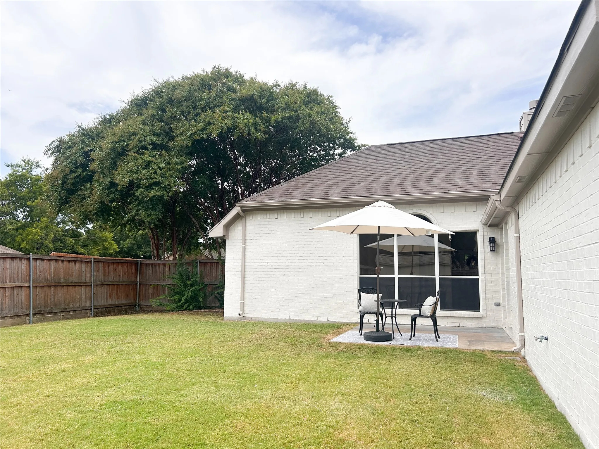 Private backyard with a spacious patio, mature shade tree, privacy fence, and plenty of room for outdoor entertaining and play.