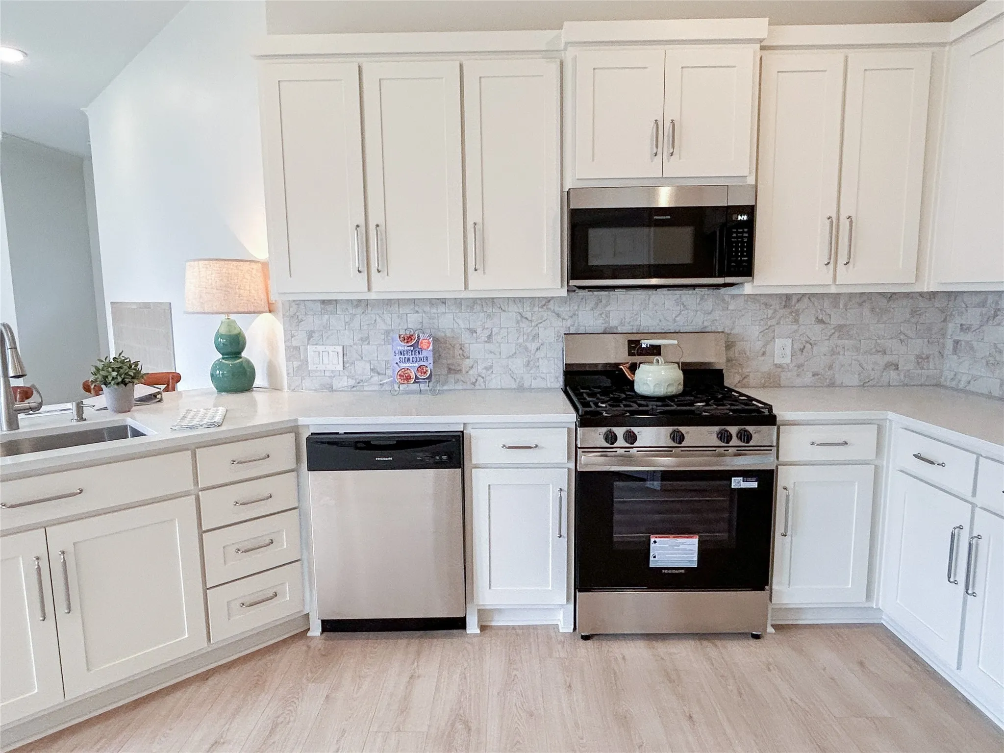 Gas stove! Bright, chef-inspired kitchen featuring white shaker cabinetry, quartz countertops, marble-look backsplash, stainless steel appliances, abundant storage, and an open, functional layout.