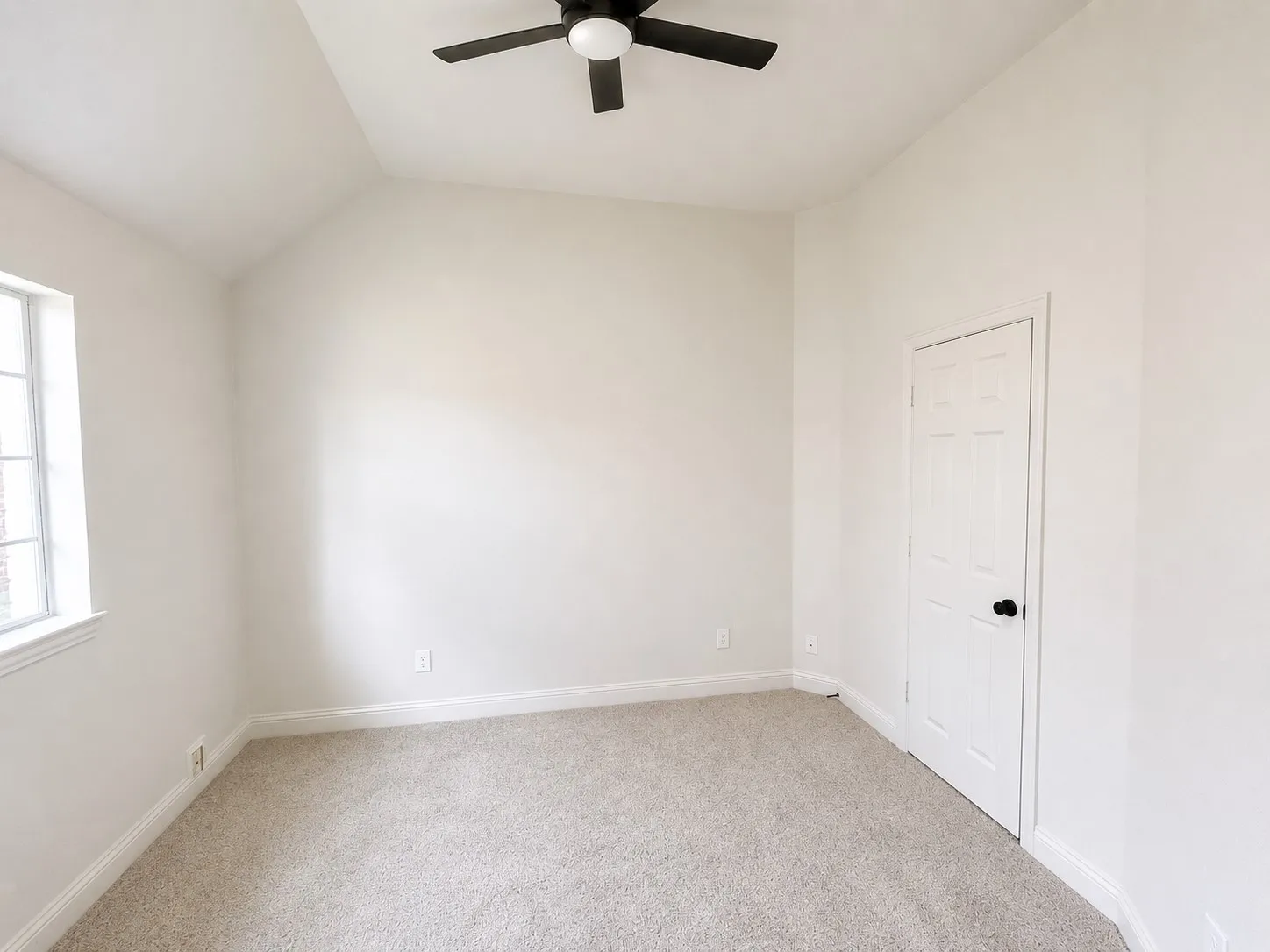 Spacious secondary bedroom featuring vaulted ceilings, a large window with natural light, and a neutral color palette.