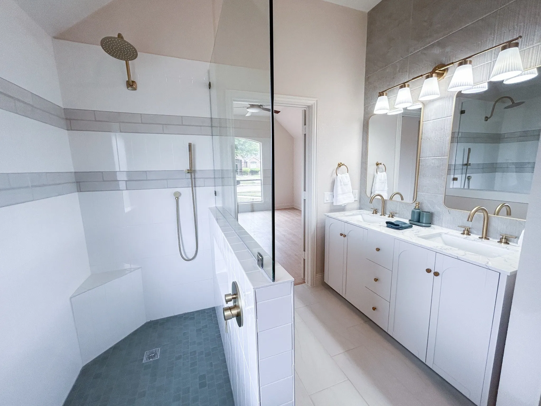 Luxurious primary bathroom featuring a spacious dual-sink vanity, elegant brass fixtures, and a large walk-in shower with designer tile.