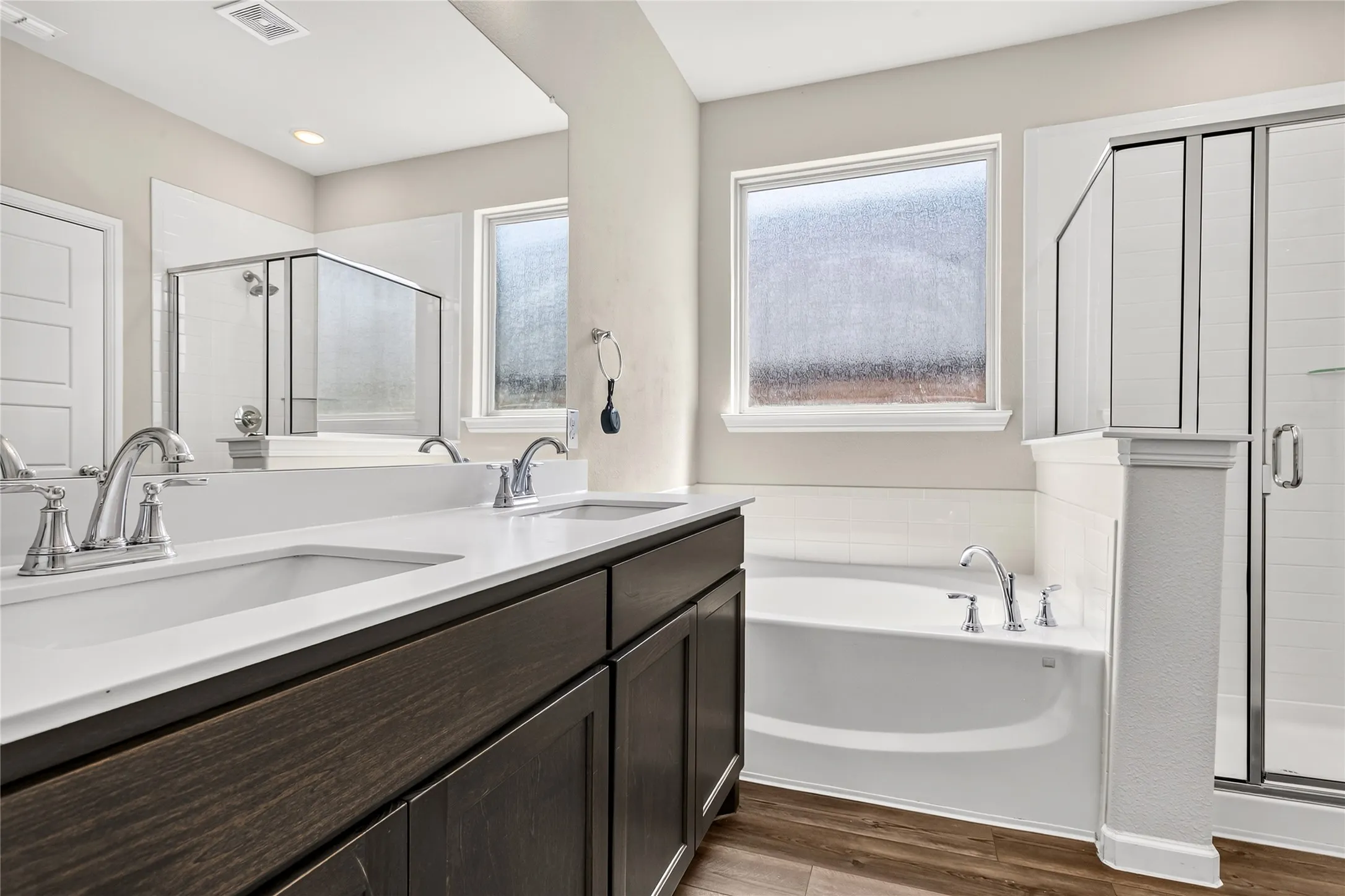 Bathroom with shower with separate bathtub, double sink vanity, and hardwood / wood-style floors