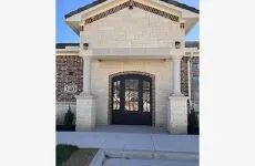 Arched entry with double doors, stone facade, brick accents, and columnar supports