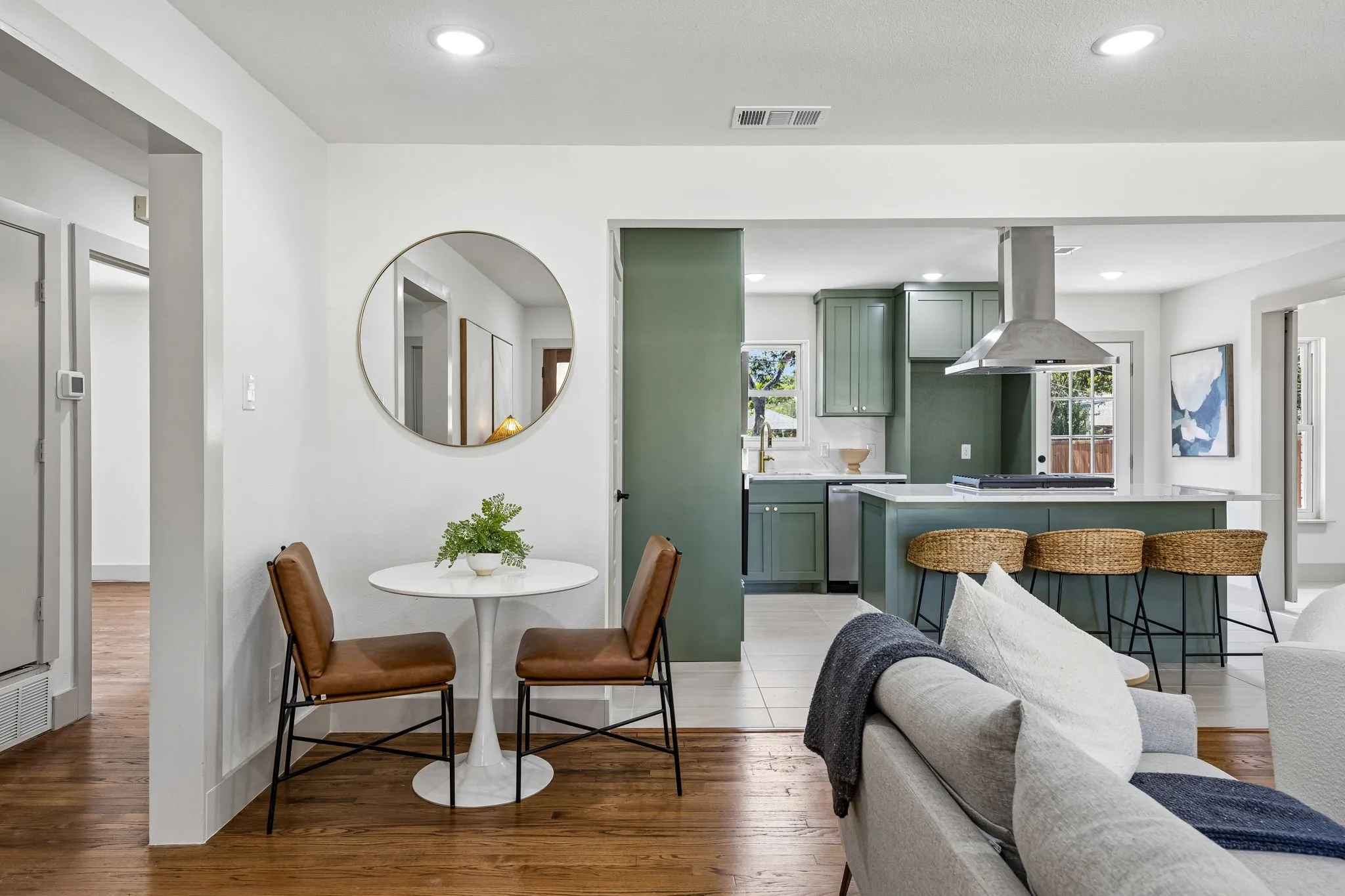 Wood-finish flooring throughout, recessed lighting, and a kitchen featuring a stainless steel range hood, ample cabinetry, and an expansive island with seating
