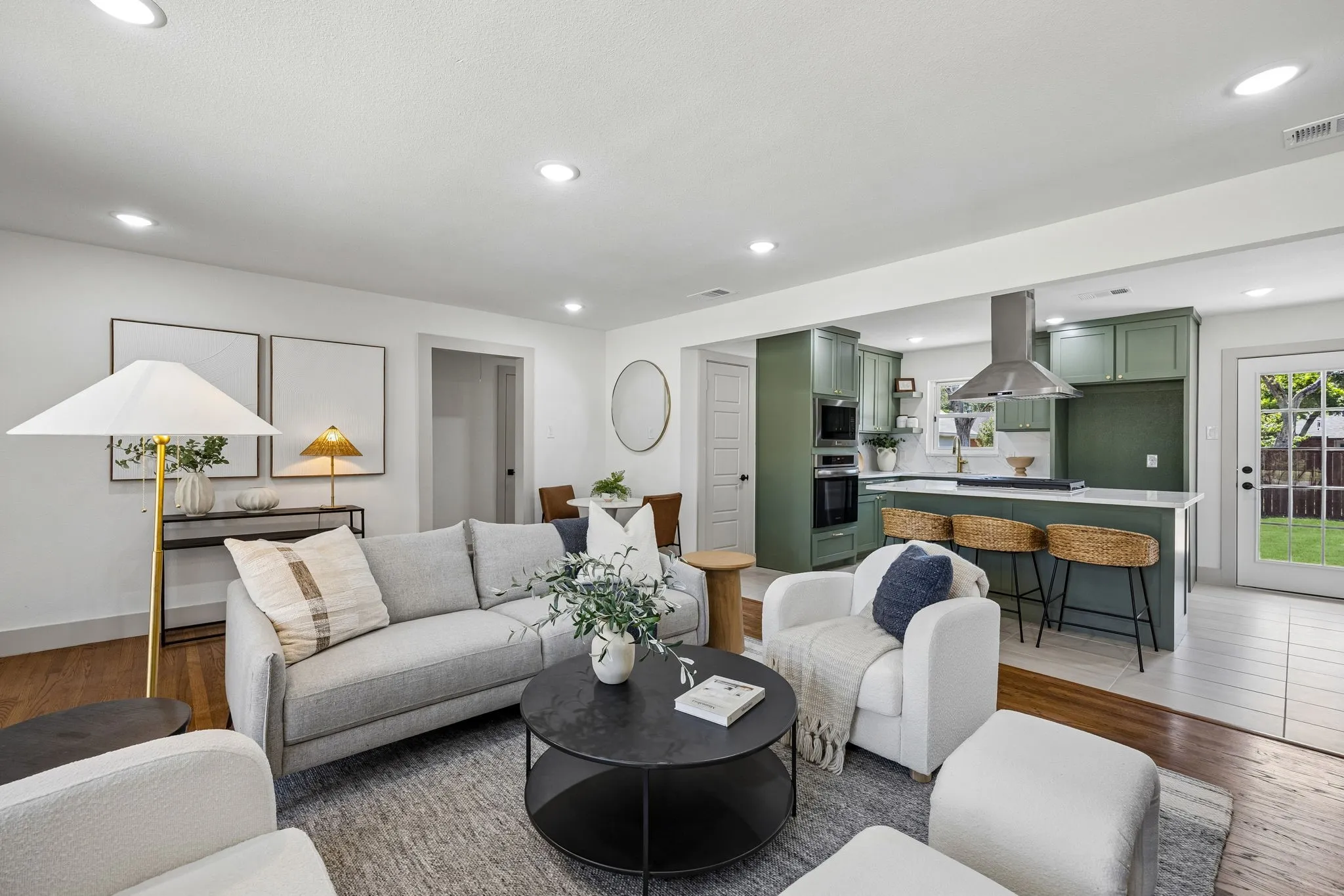 Recessed lighting throughout, wood-finish flooring, kitchen island with seating, stainless steel range hood, and a full-light door to the exterior