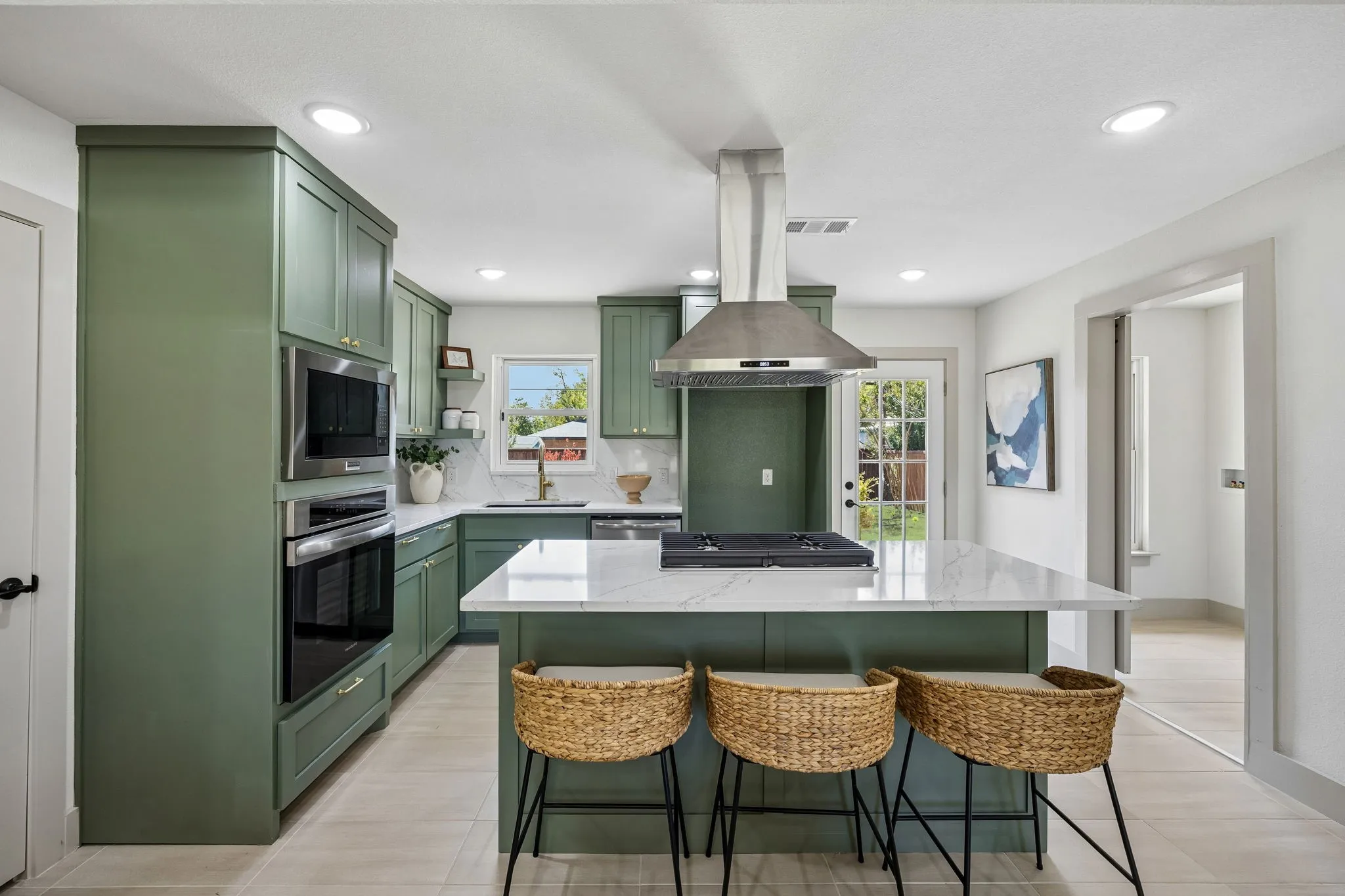 Kitchen featuring green cabinetry, stainless steel appliances, a center island with a cooktop, stone countertops, and recessed lighting