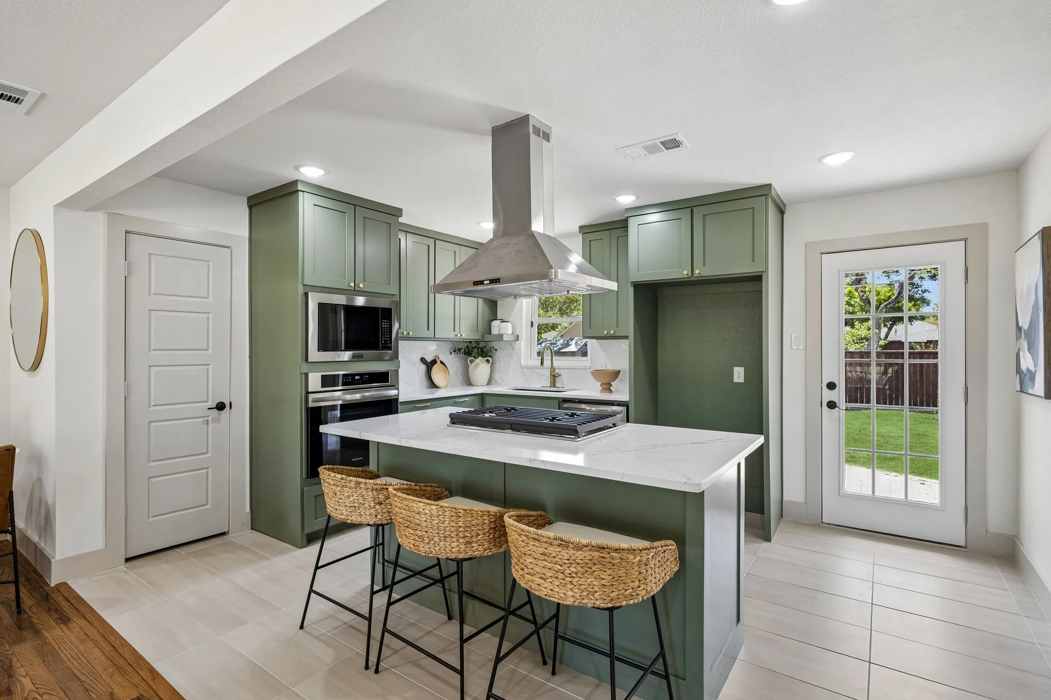 Open-concept kitchen featuring olive green cabinetry, stainless steel appliances, a center island with a white countertop, and light-colored tile flooring