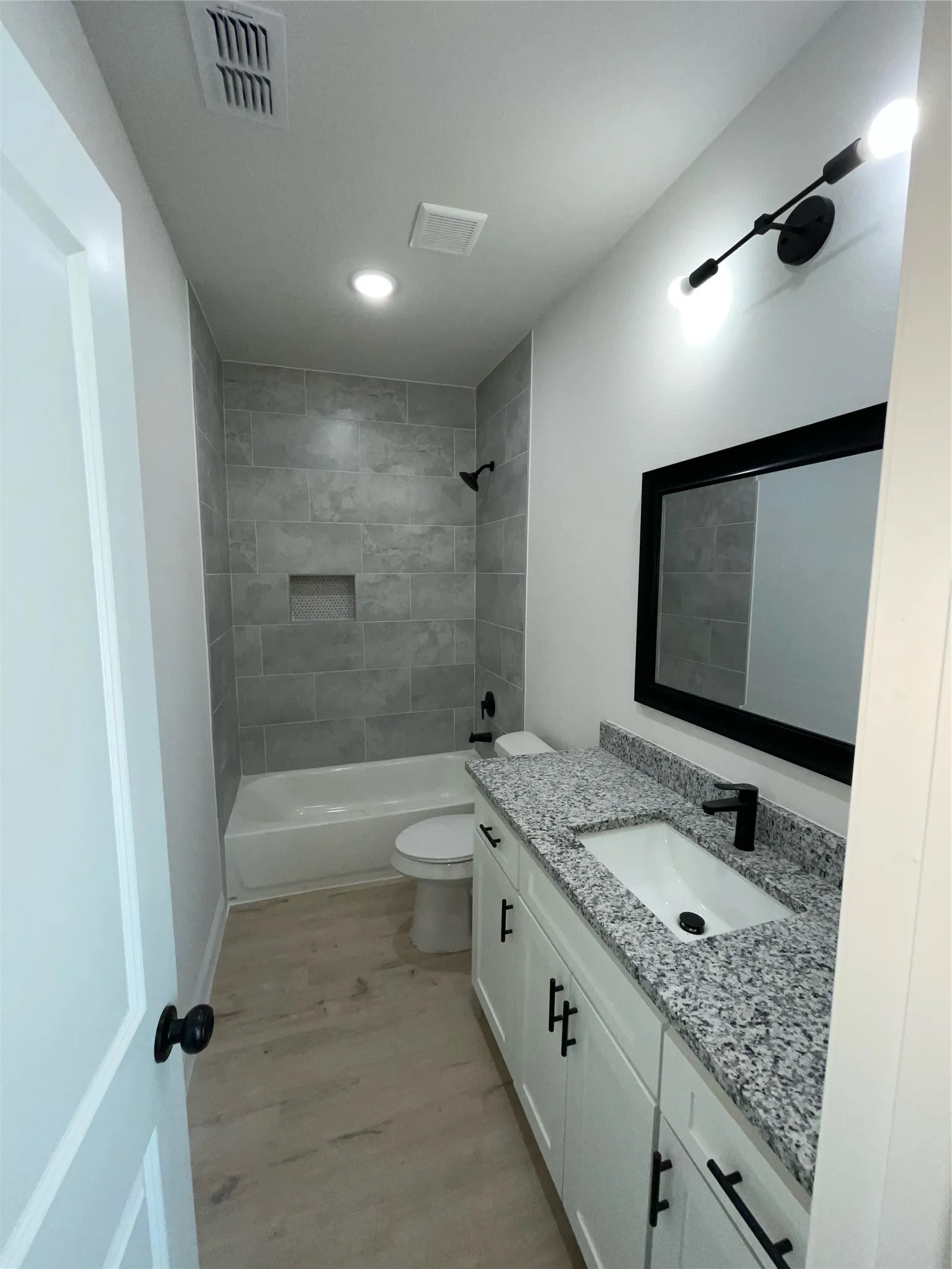 Contemporary bathroom featuring a white vanity with granite-style countertop, undermount sink, and matte black faucet