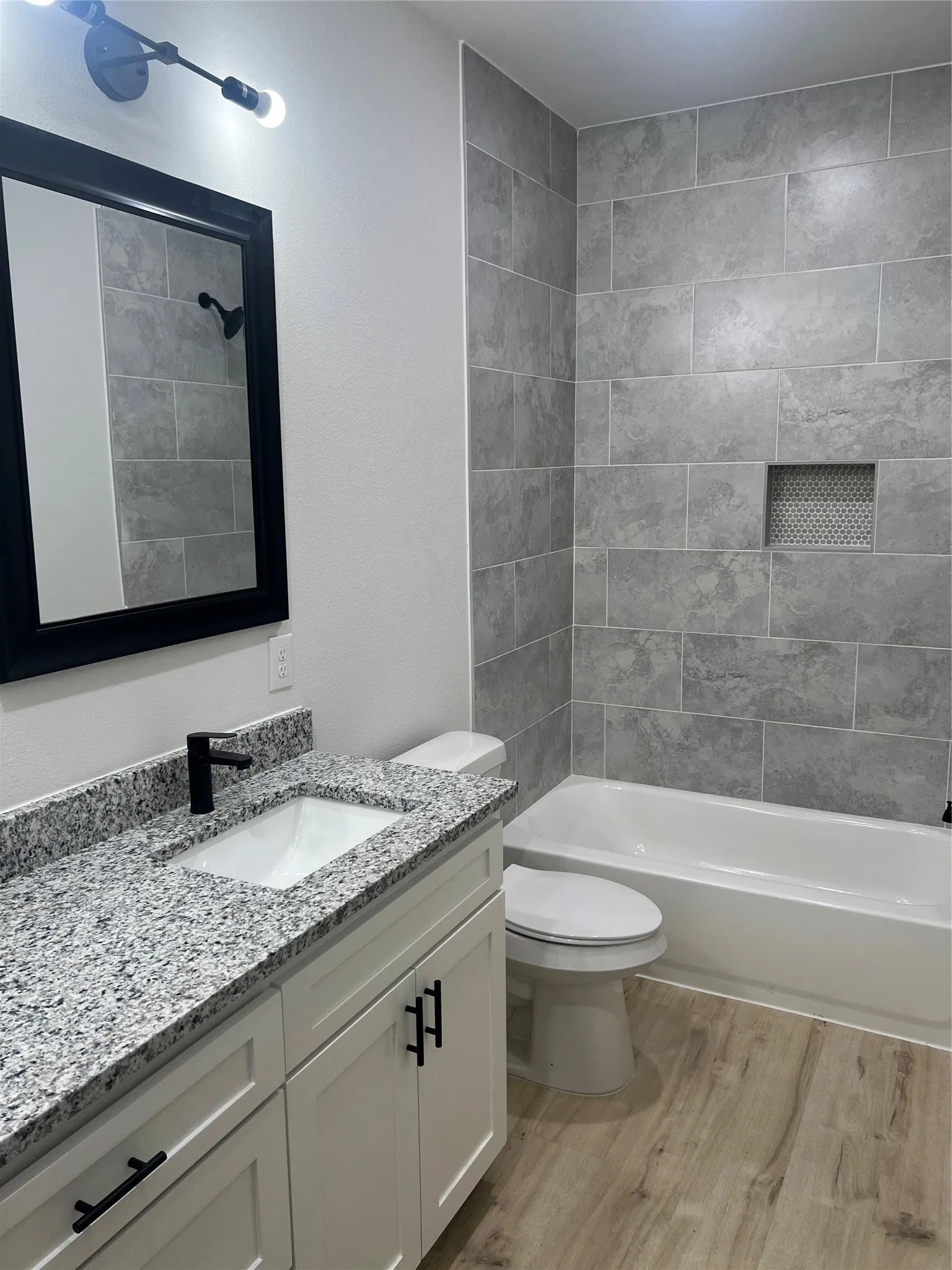 White shaker vanity with granite countertop, undermount sink, and matte black hardware