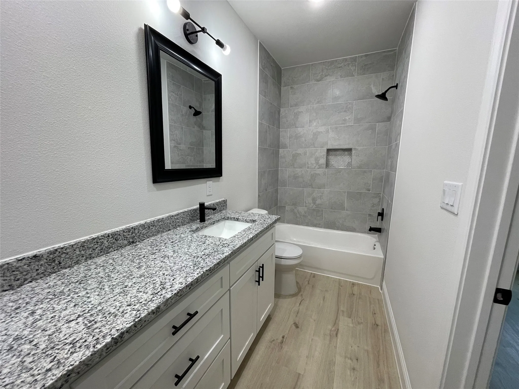 Spacious vanity with speckled countertop, undermount sink, and matte black faucet