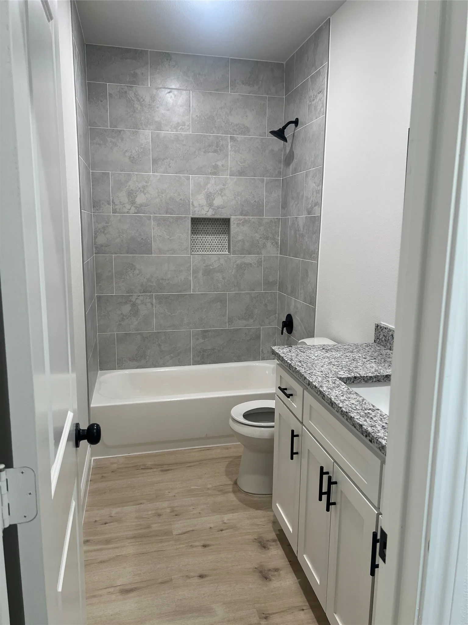 Tub and shower combination with gray tile surround and recessed niche