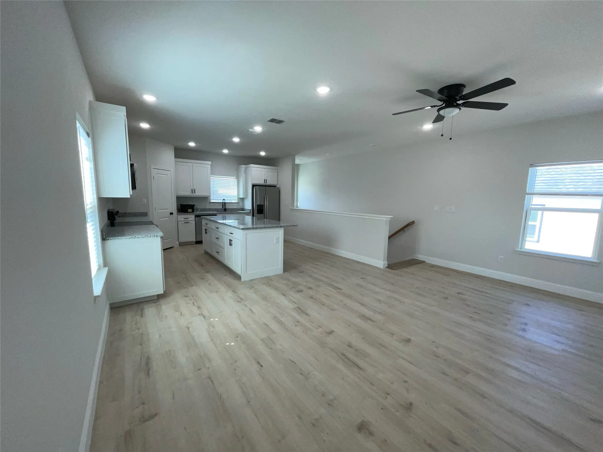 Open-concept living space featuring wood-finish flooring, recessed lighting, and a modern ceiling fan