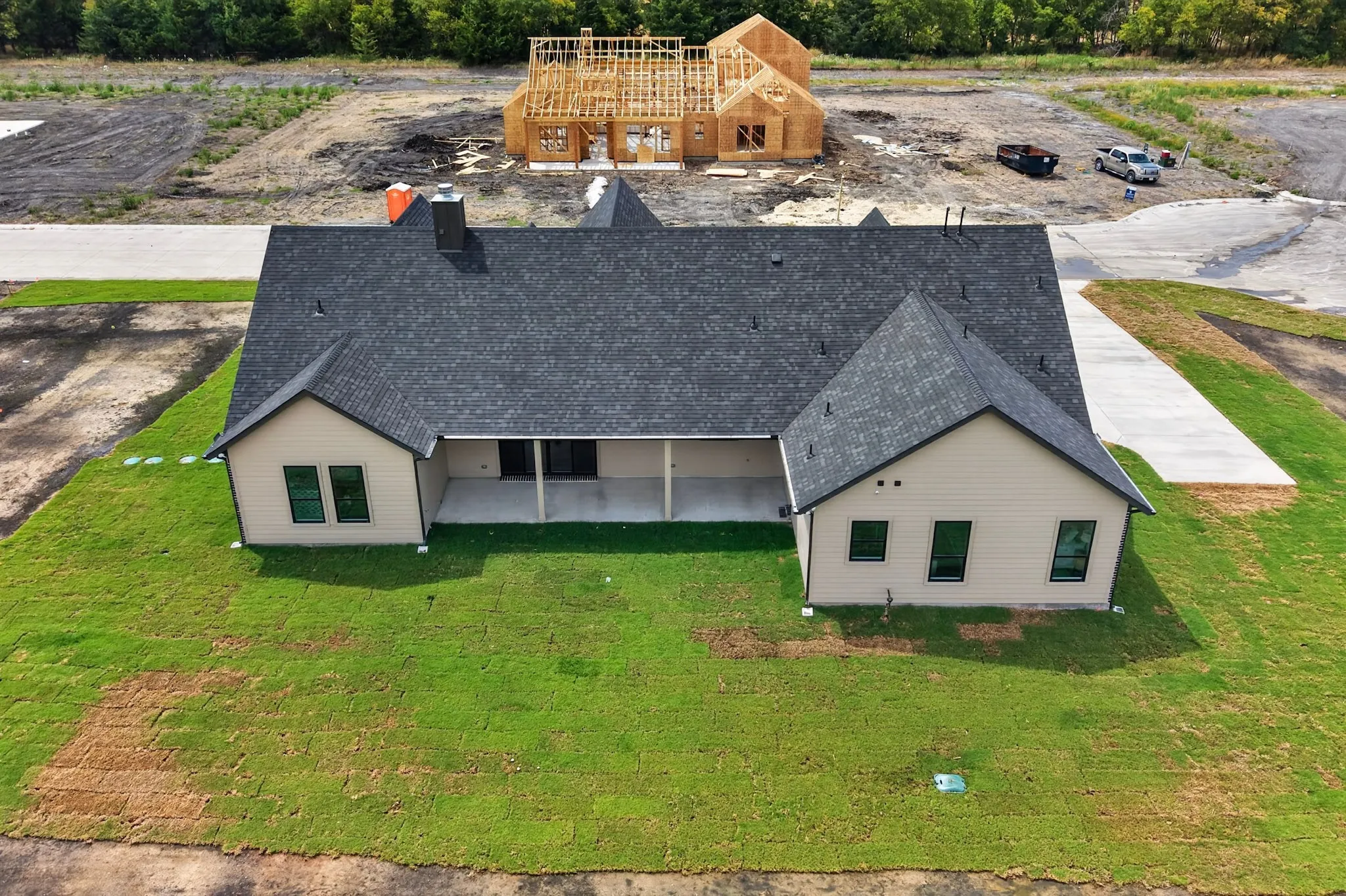 Pitched dark shingle roof, light-toned siding, and a covered back patio