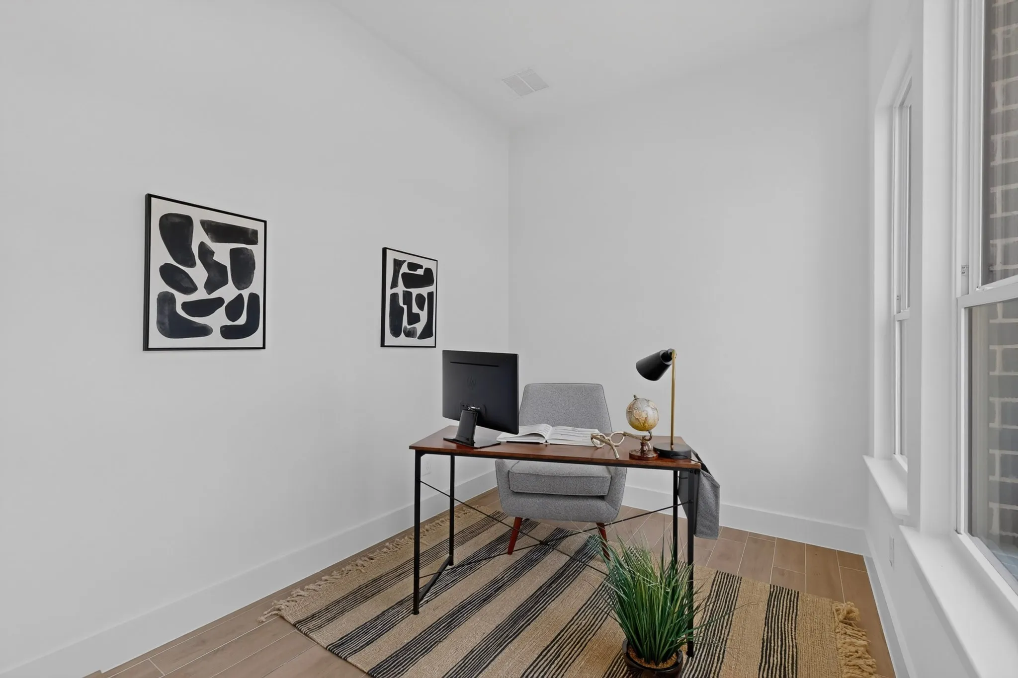 Light-filled room featuring wood-finish flooring, white walls, and a large window