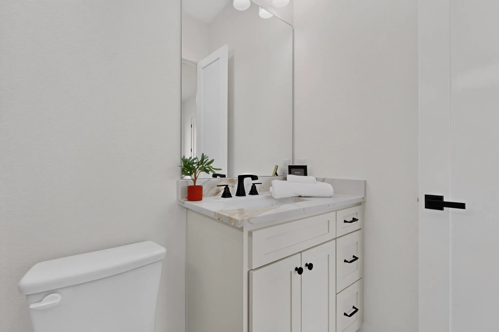 White vanity with a marble-finish countertop, undermount sink, and black fixtures