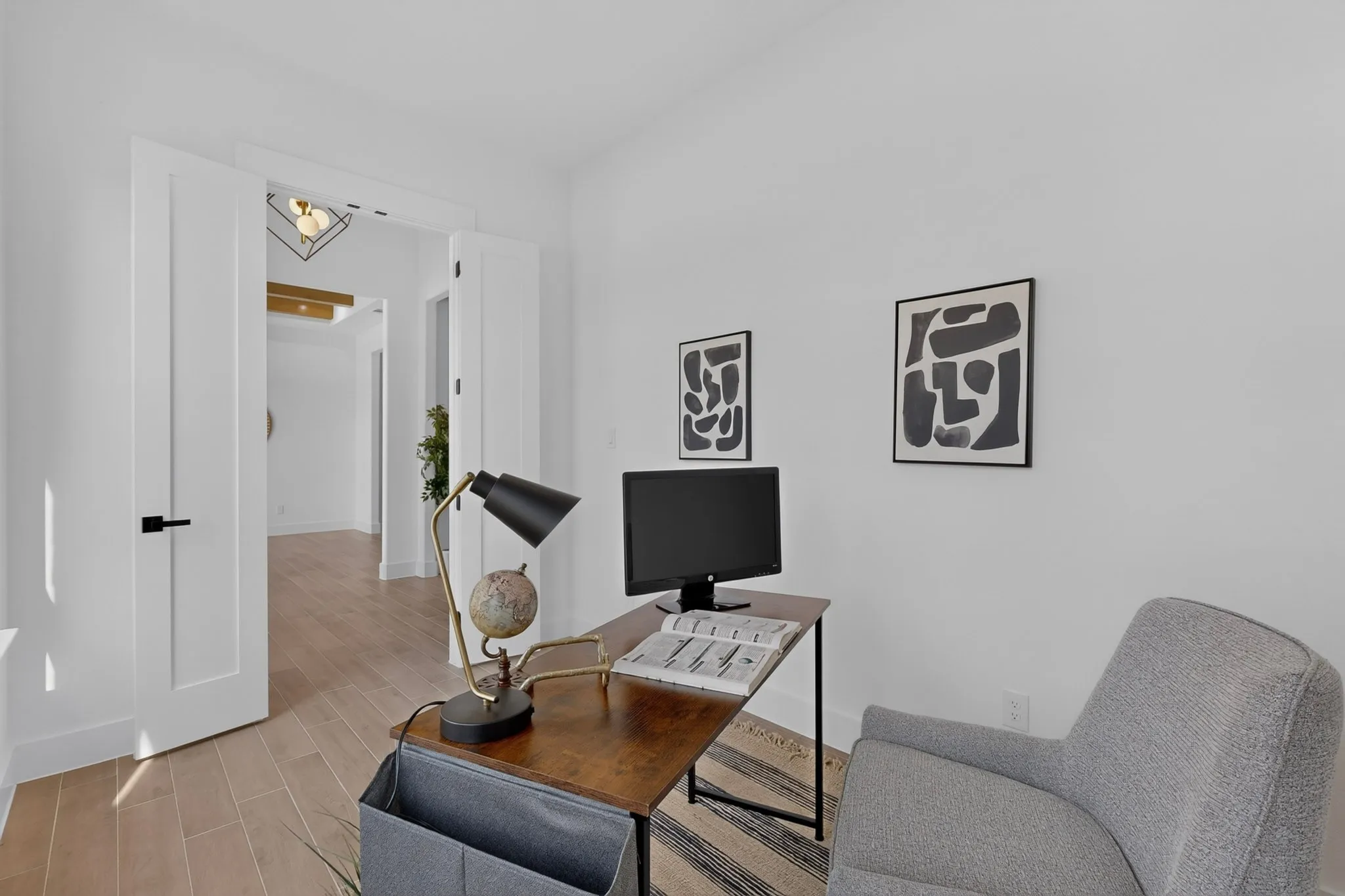 Wood-finish flooring, white solid core doors with matte black hardware, and crisp white walls throughout