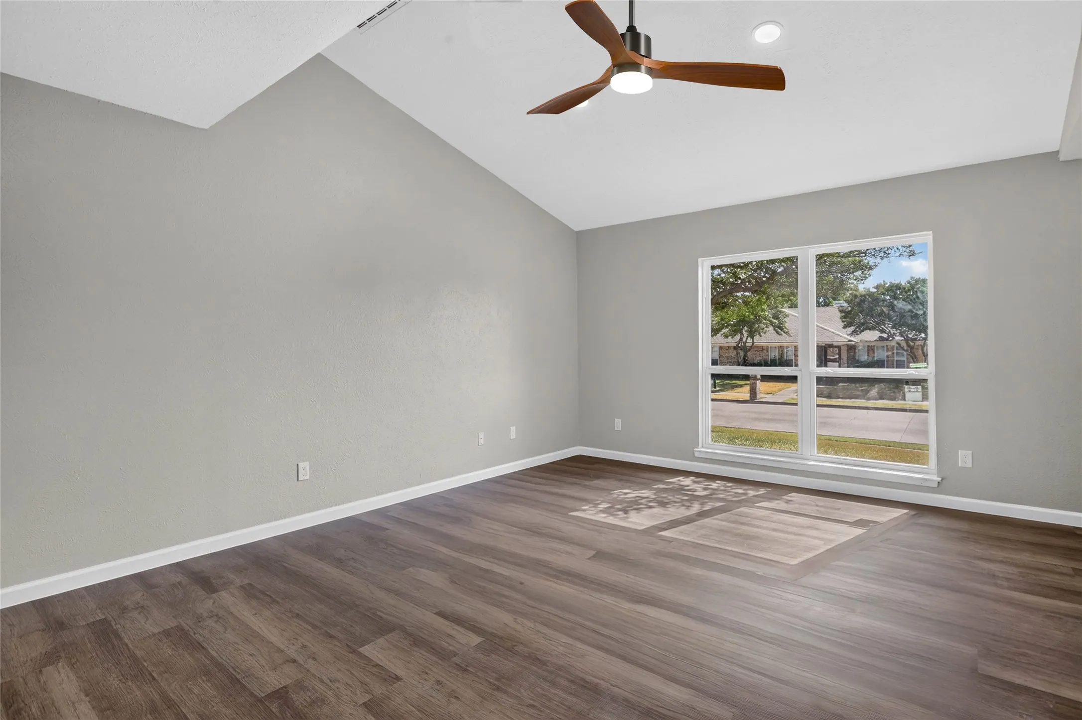 Vaulted ceiling with a contemporary ceiling fan, recessed lighting, expansive window, and wood-finish flooring